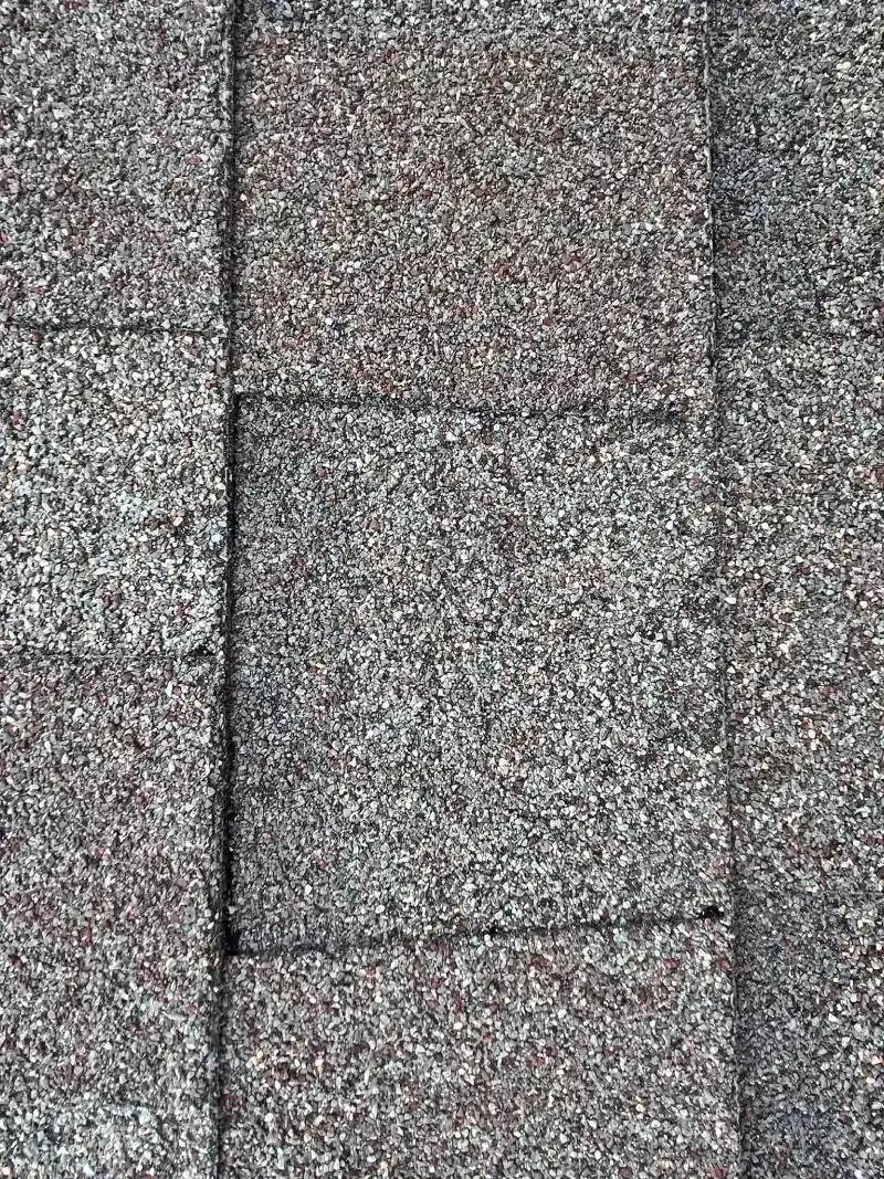 Close-up of a gray, textured roof with rectangular shingles, arranged in rows.