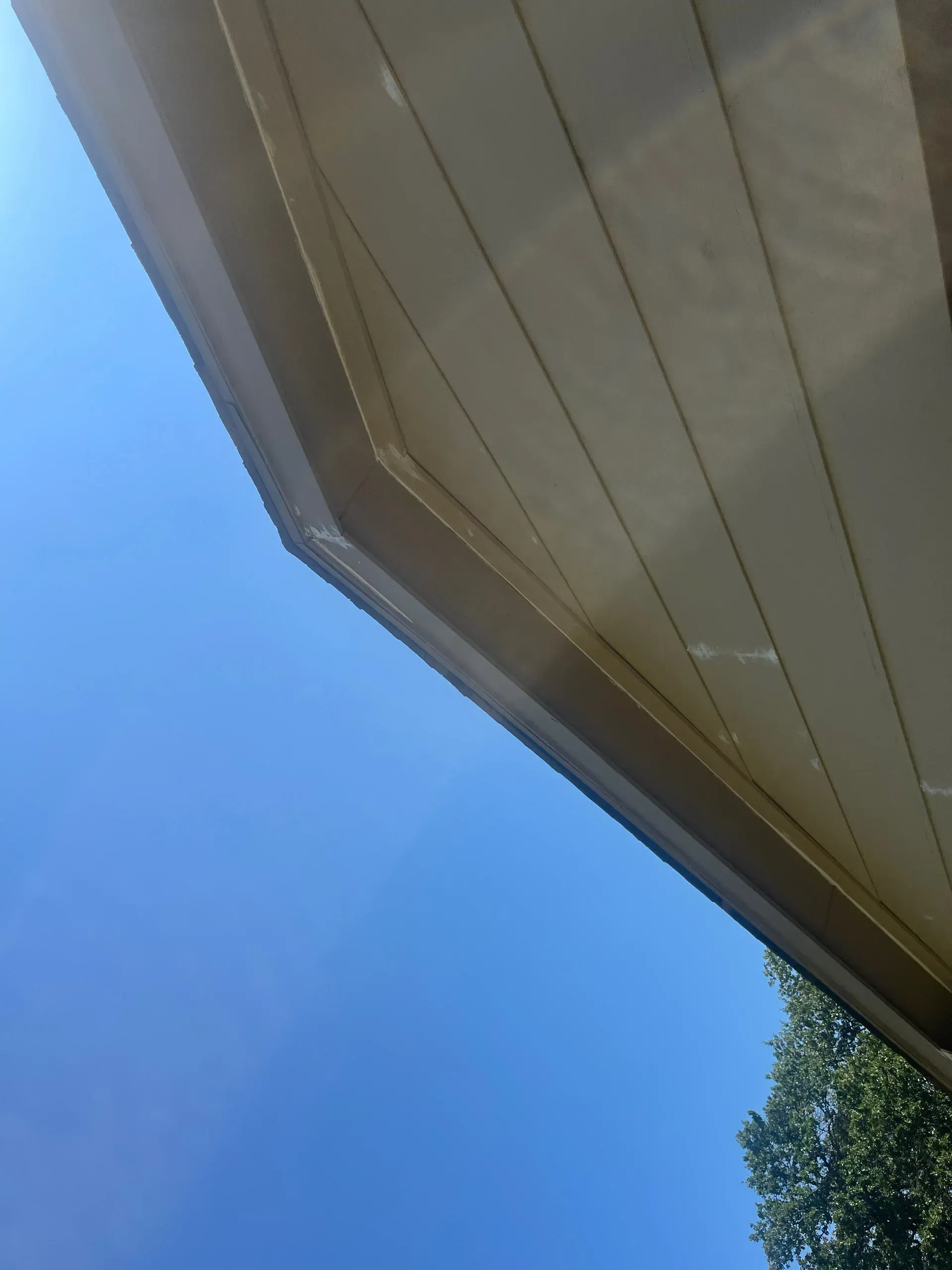 Beige roof eaves against a bright blue sky.