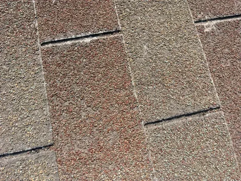 Close-up of asphalt shingles on a roof, displaying alternating rows of brown and tan colors.