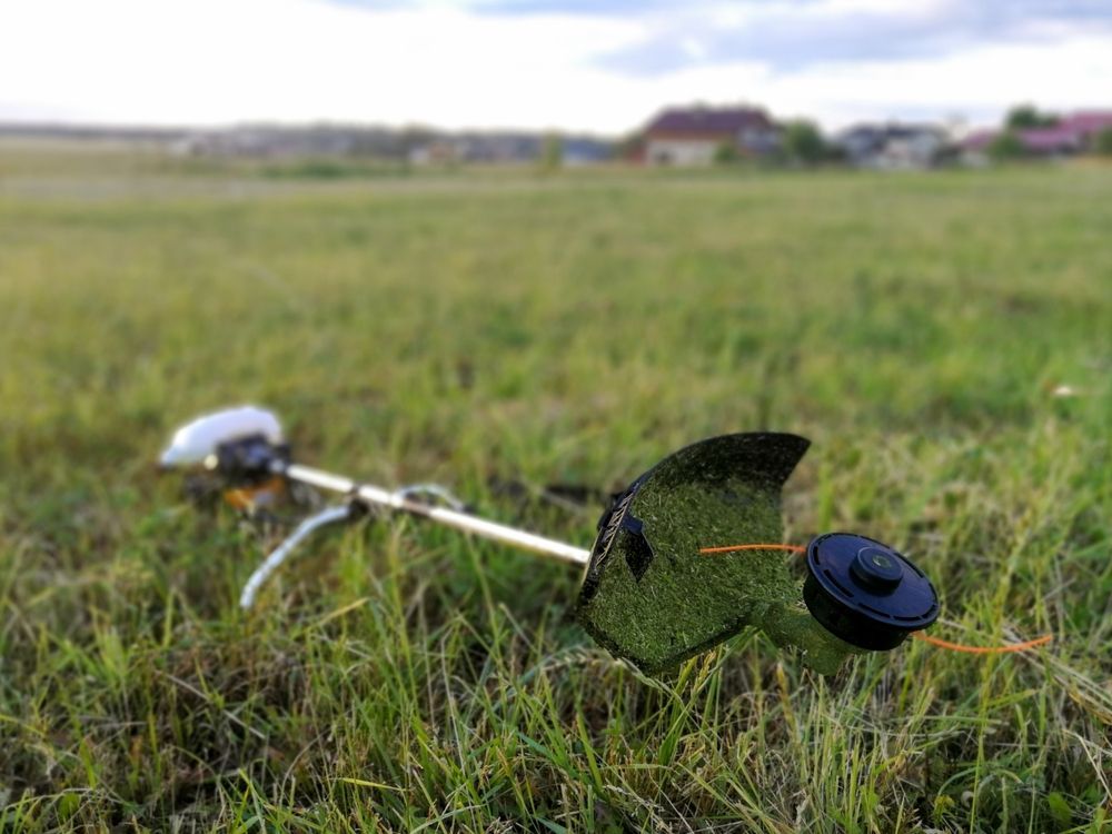 Whipper Snipper Lying in a Grassy Field — Professional Small Engines in Aitkenvale, QLD