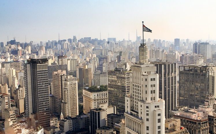Vista aérea do horizonte denso e cinzento de São Paulo, Brasil, com o icônico edifício da Banespa ostentando sua bandeira.