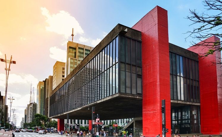 O Museu de Arte de São Paulo (MASP), com seu icônico edifício de vidro suspenso entre grandes pilares de concreto vermelho vivo.