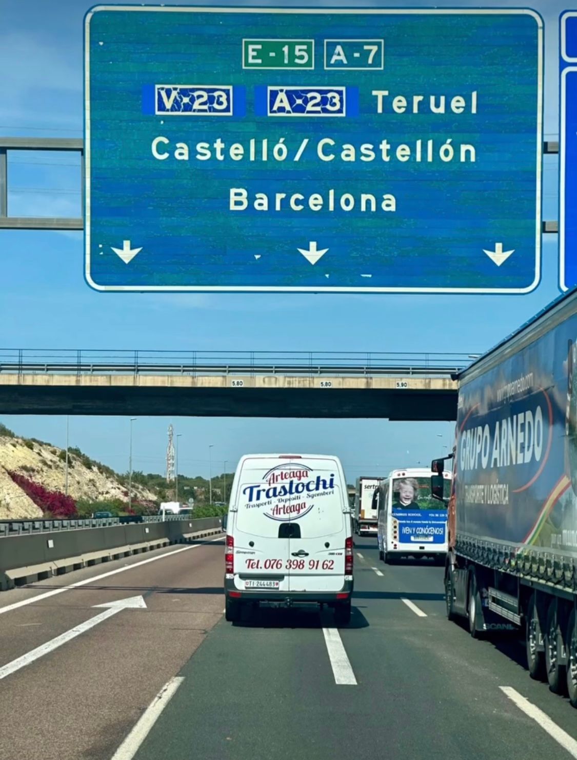 A white van is driving down a highway under a sign that says castelo / castellon barcelona