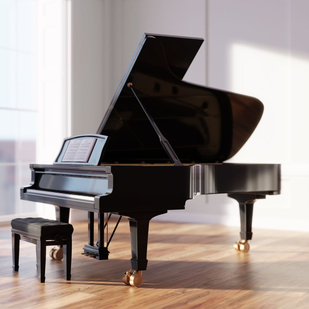 A grand piano is sitting in an empty room next to a window.