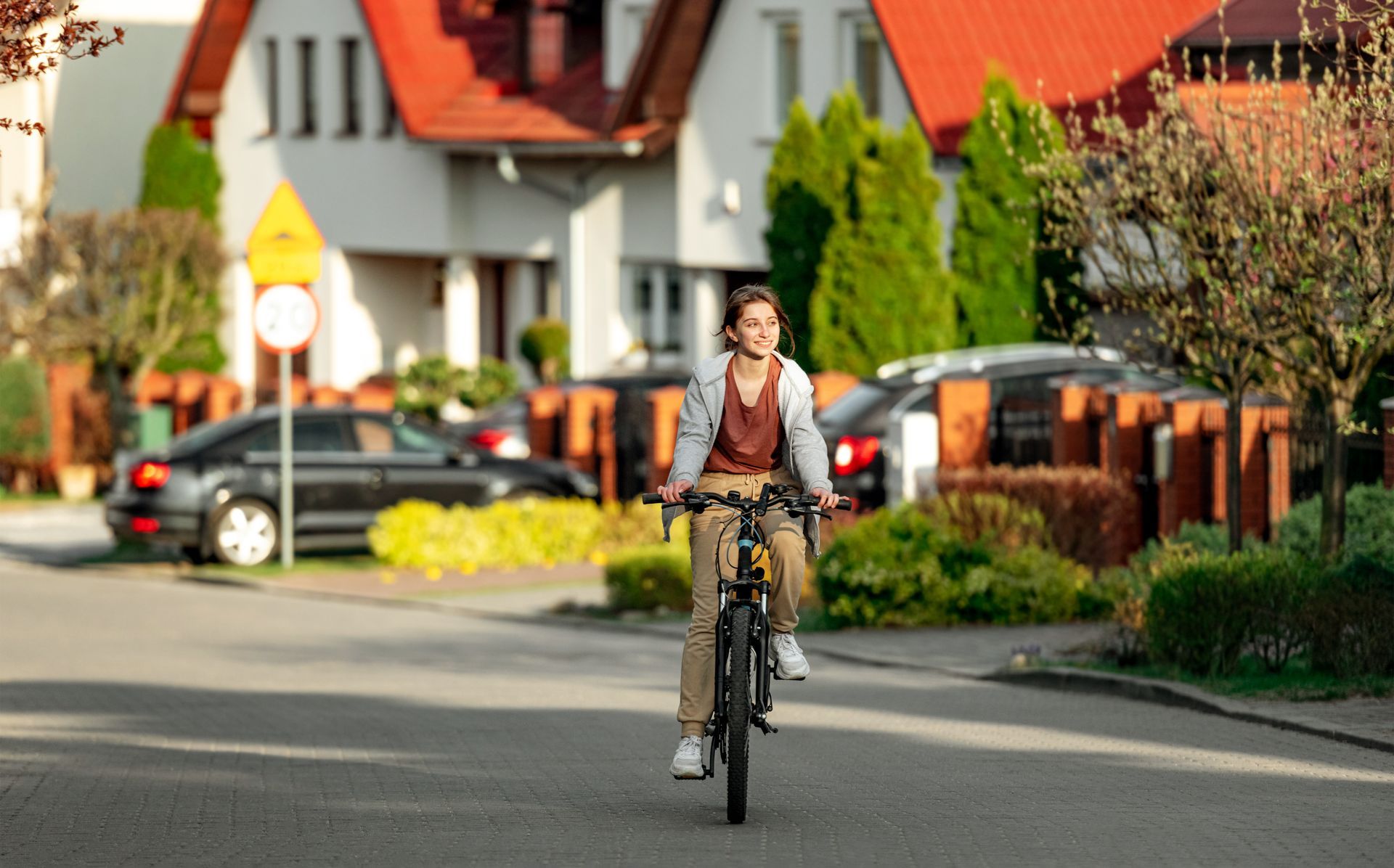 A woman is riding a bike down a street in front of a house.