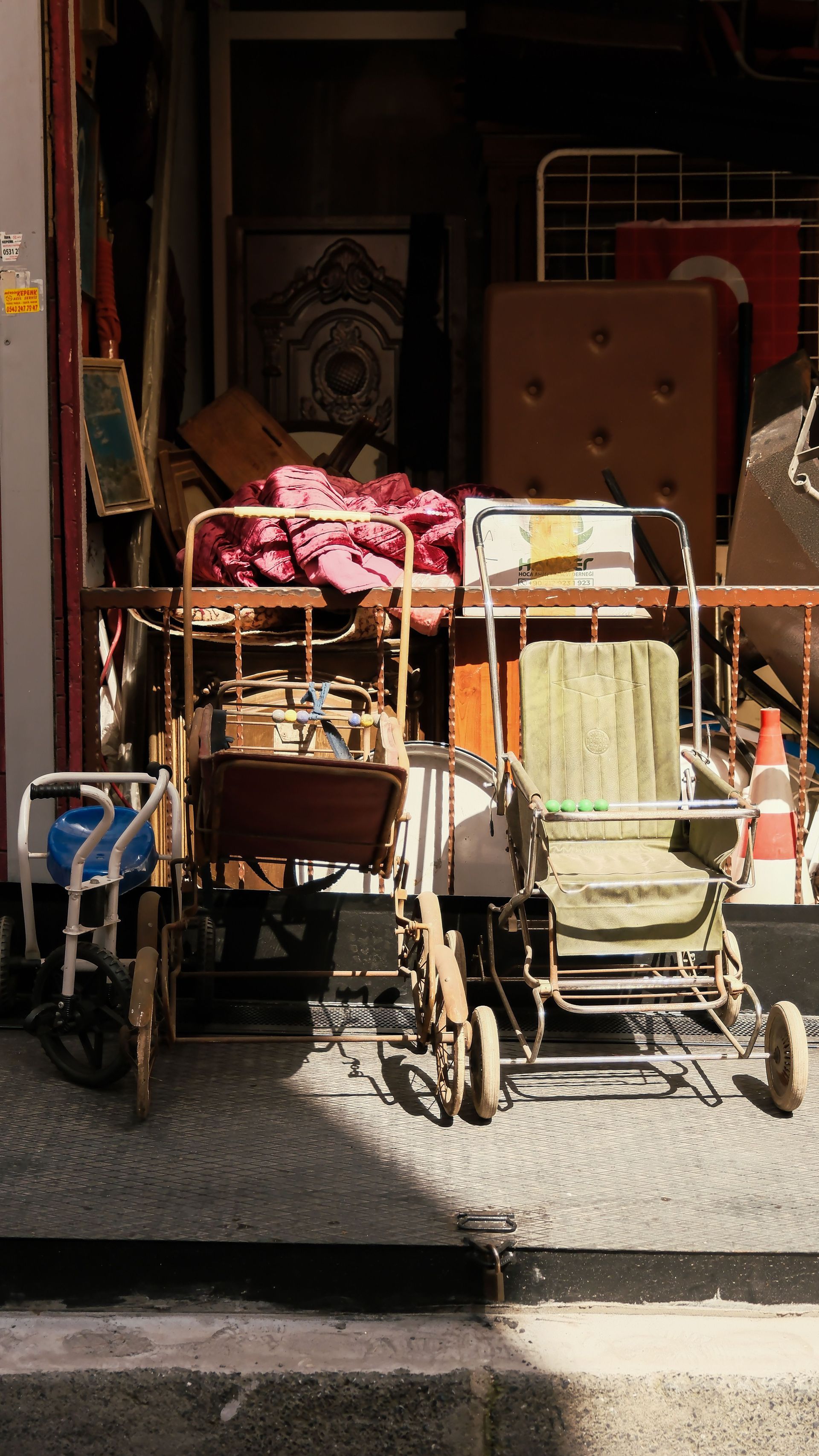 Shopping carts and stacked luggage outside a dim storefront, with a pink bag and boxes visible