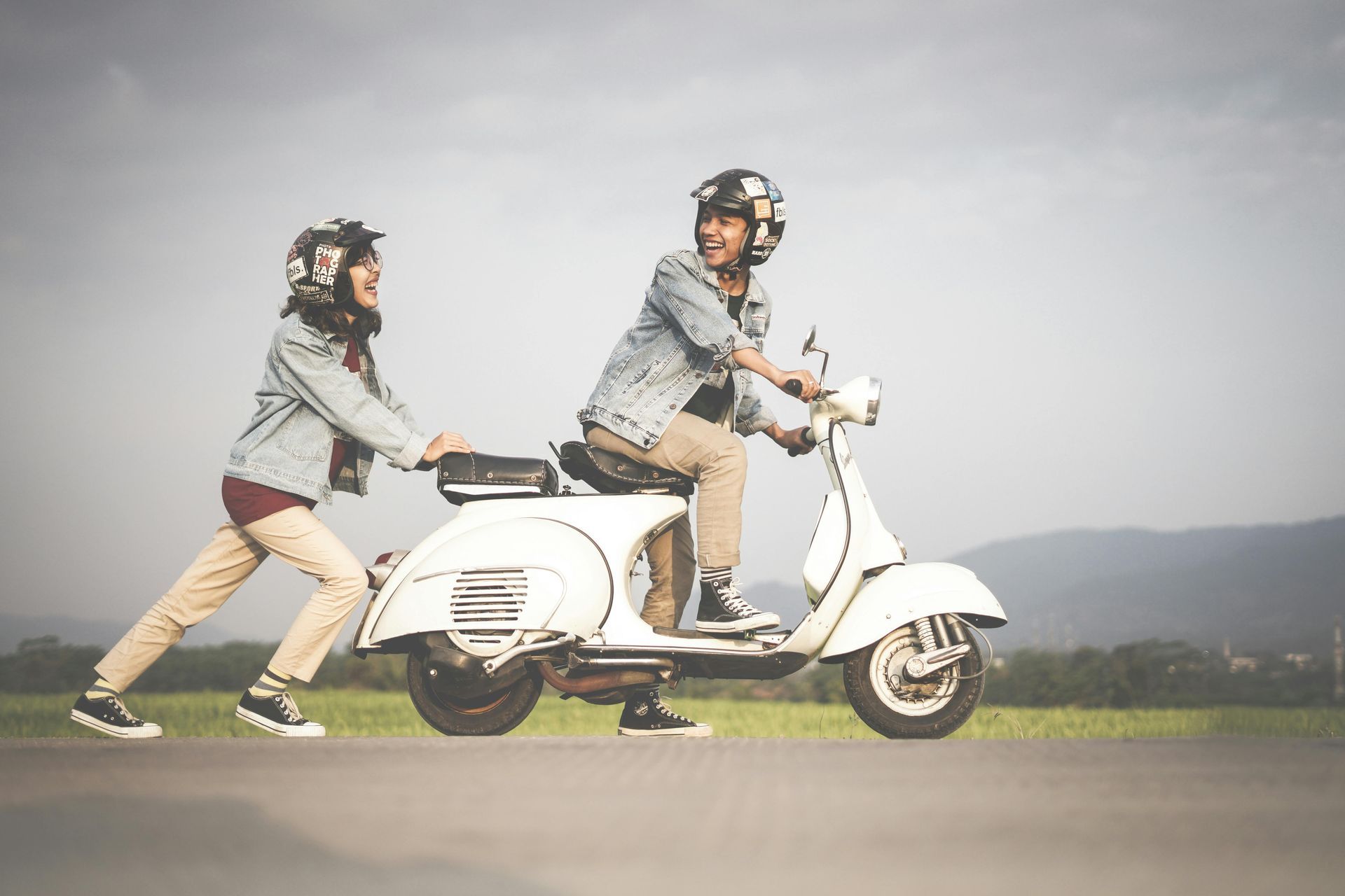 A man and a woman are riding a scooter down a road.