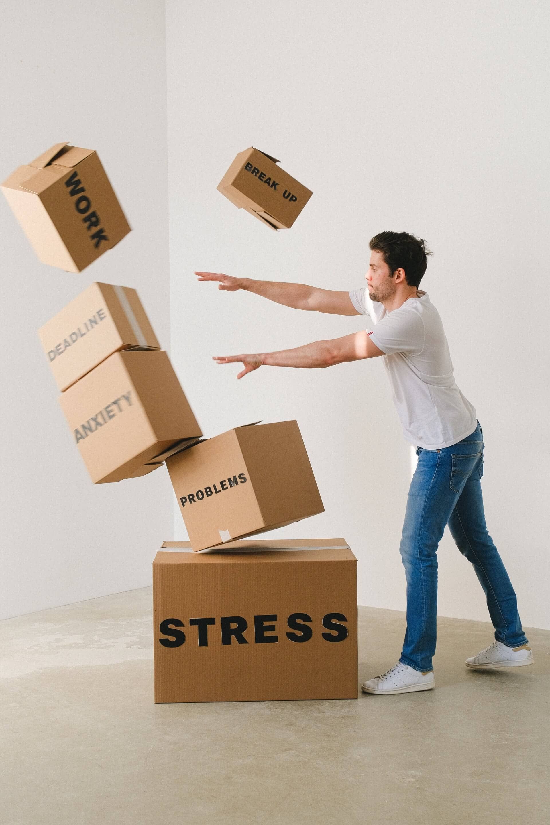 A man is standing next to a stack of cardboard boxes with the word stress on them.