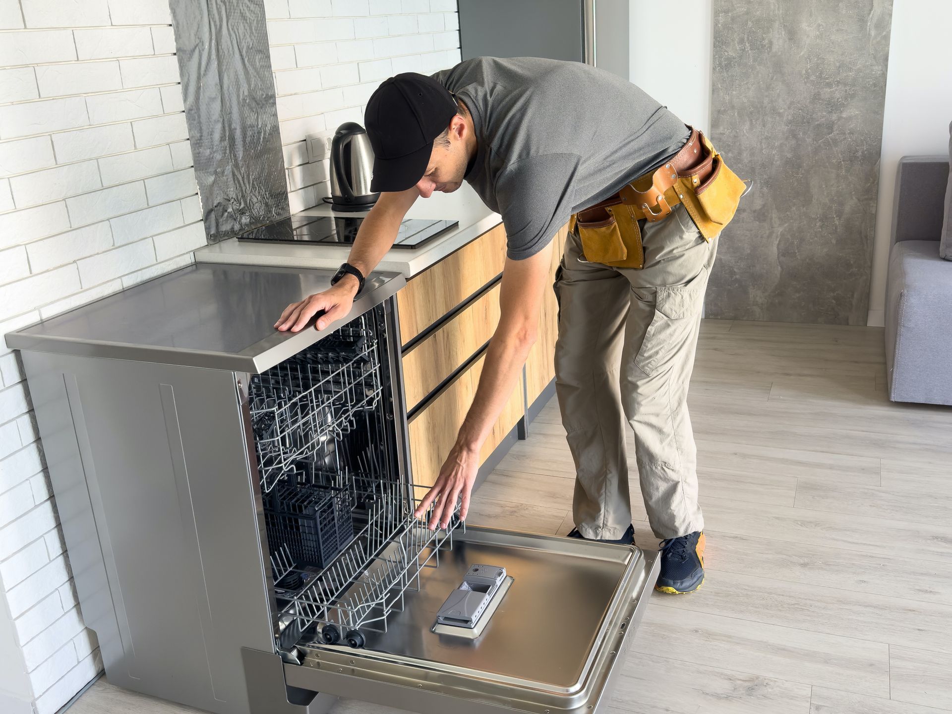 Repair service worker repairing a dishwasher appliance in the kitchen.