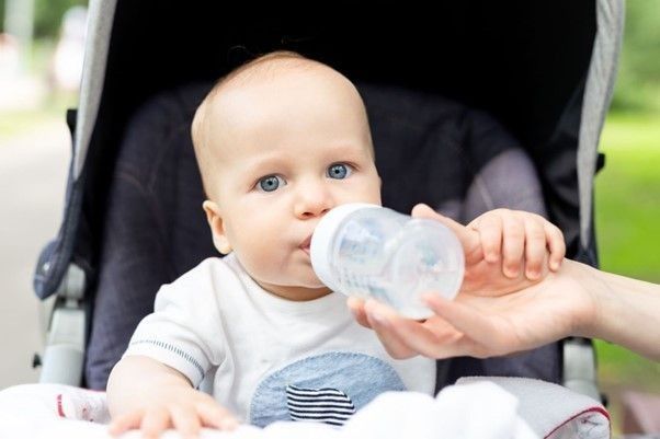 baby sitting in a pram drinking water from a bottle