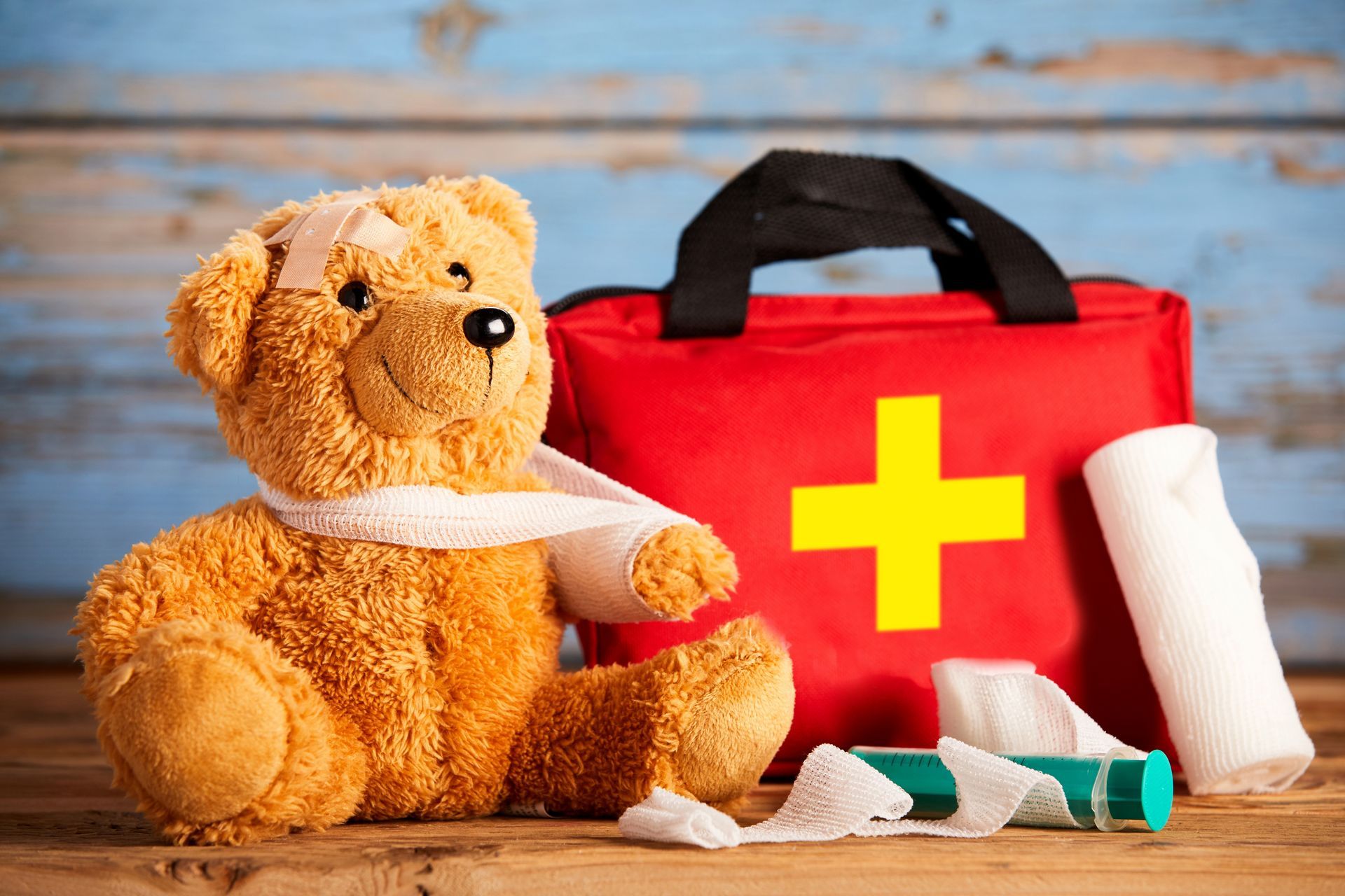 Teddy Bear with bandage and first aid kit next to it