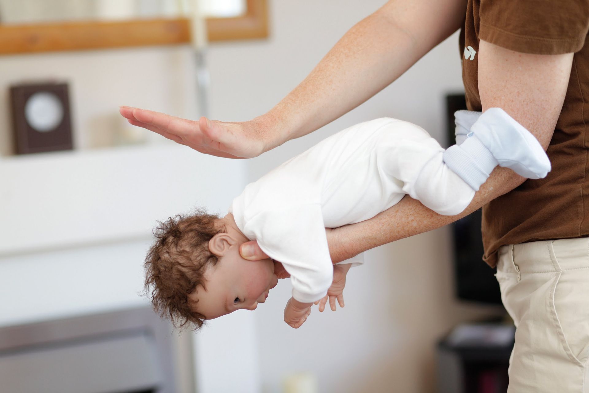 Adult performing first aid back blows to relieve infant choking.