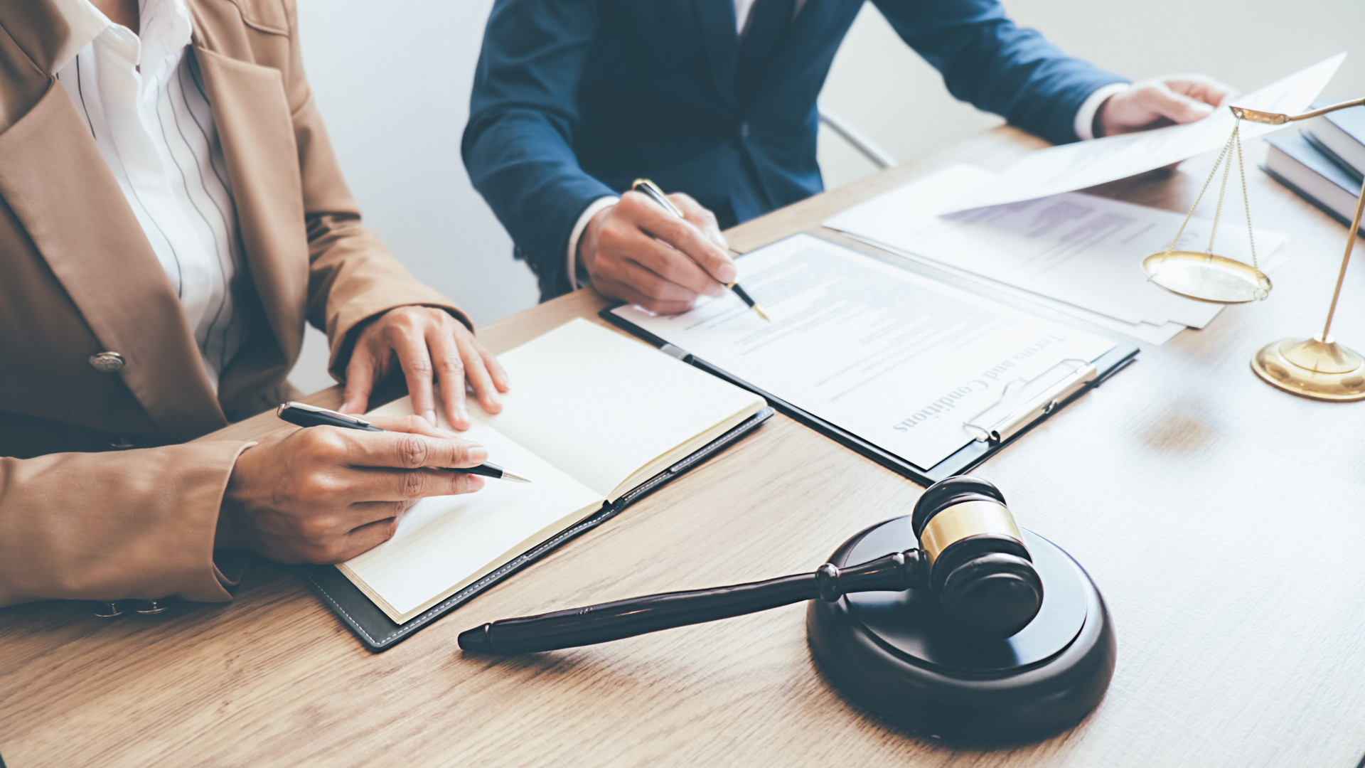 A man and a woman are sitting at a table with papers and a gavel.