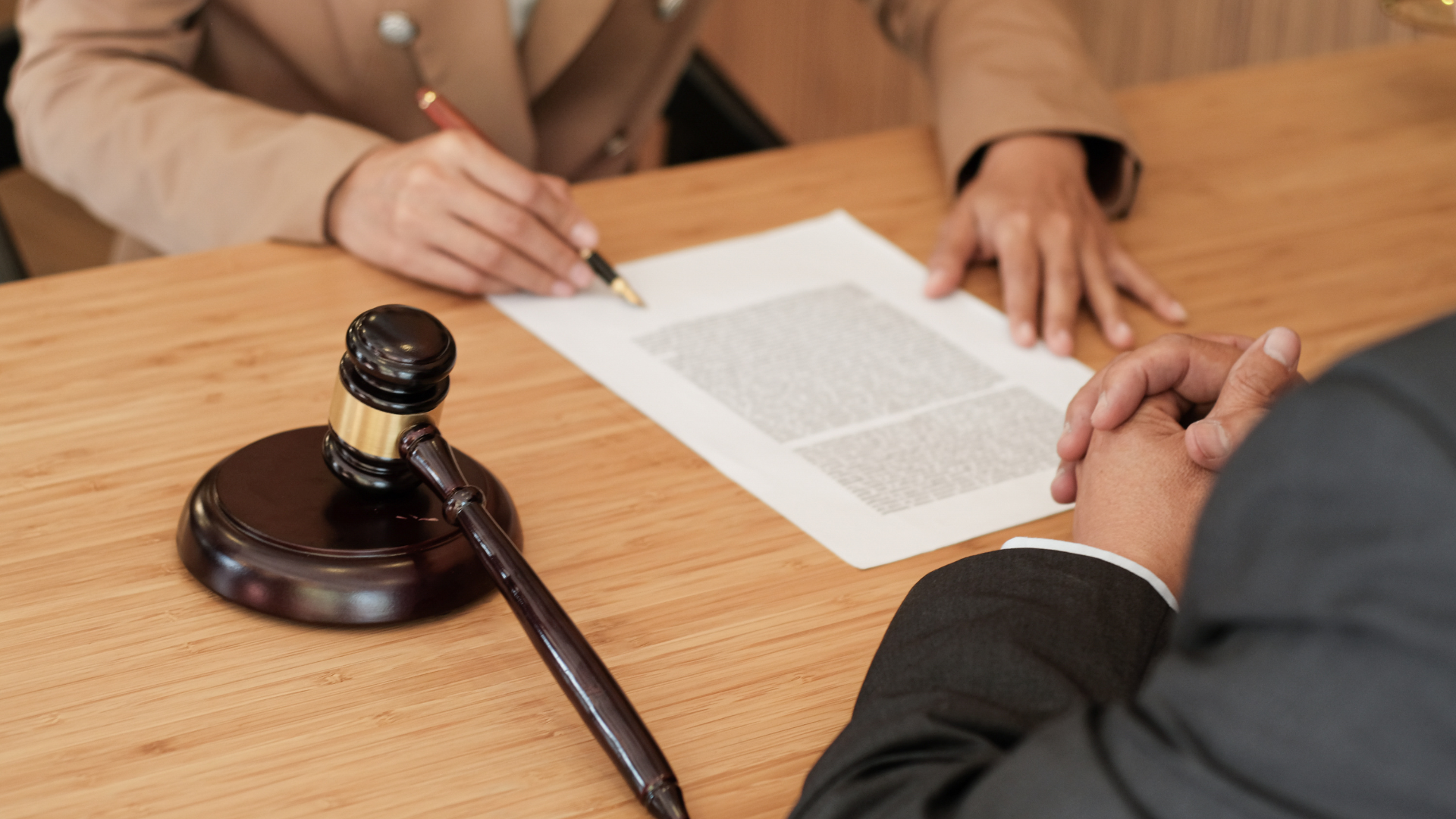A woman is writing on a piece of paper next to a judge 's gavel.