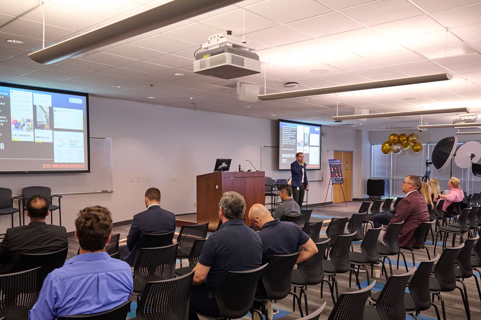 A group of people are sitting in a lecture hall watching a presentation.