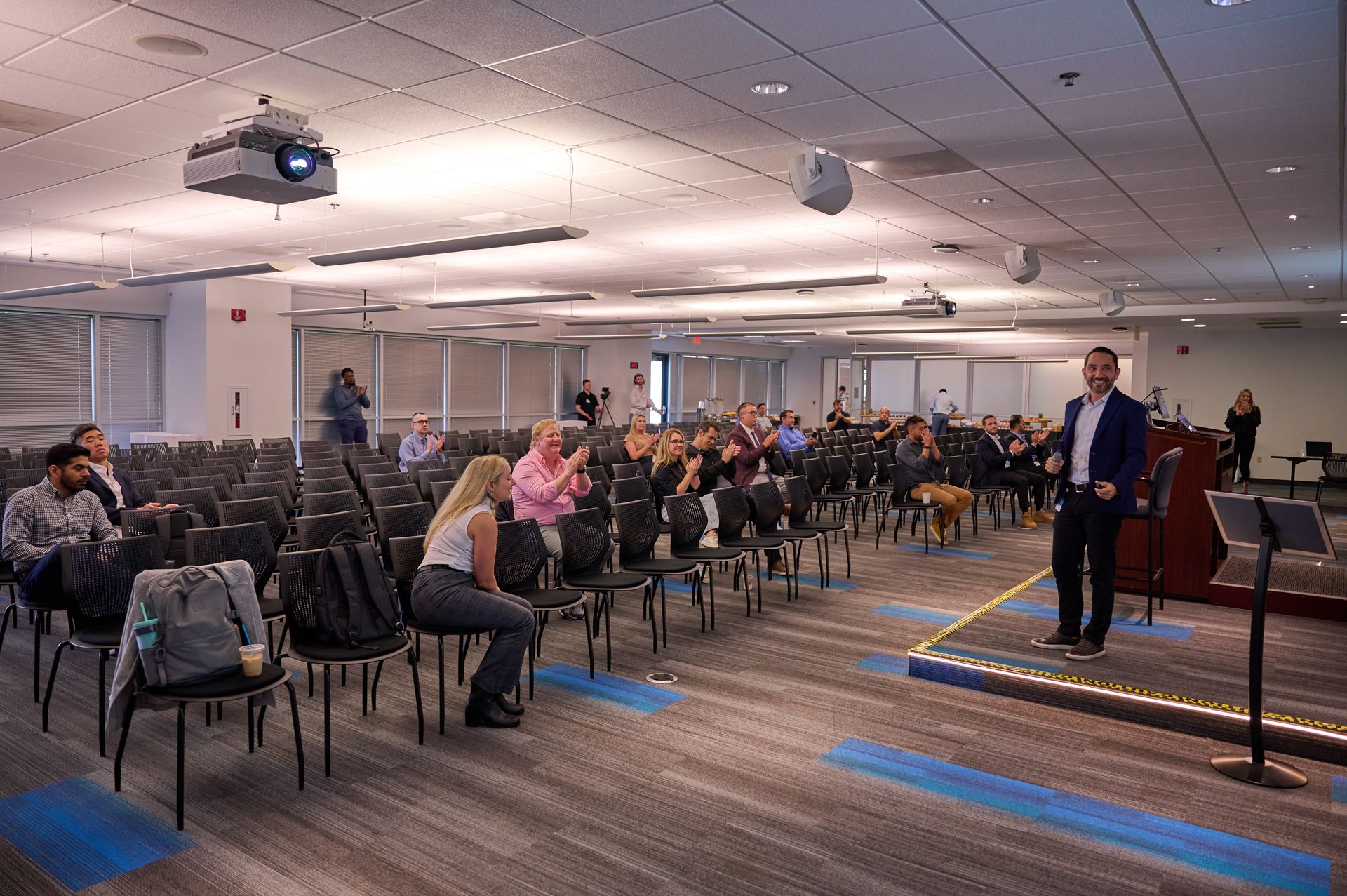 A man is giving a presentation in front of a large audience in a conference room.