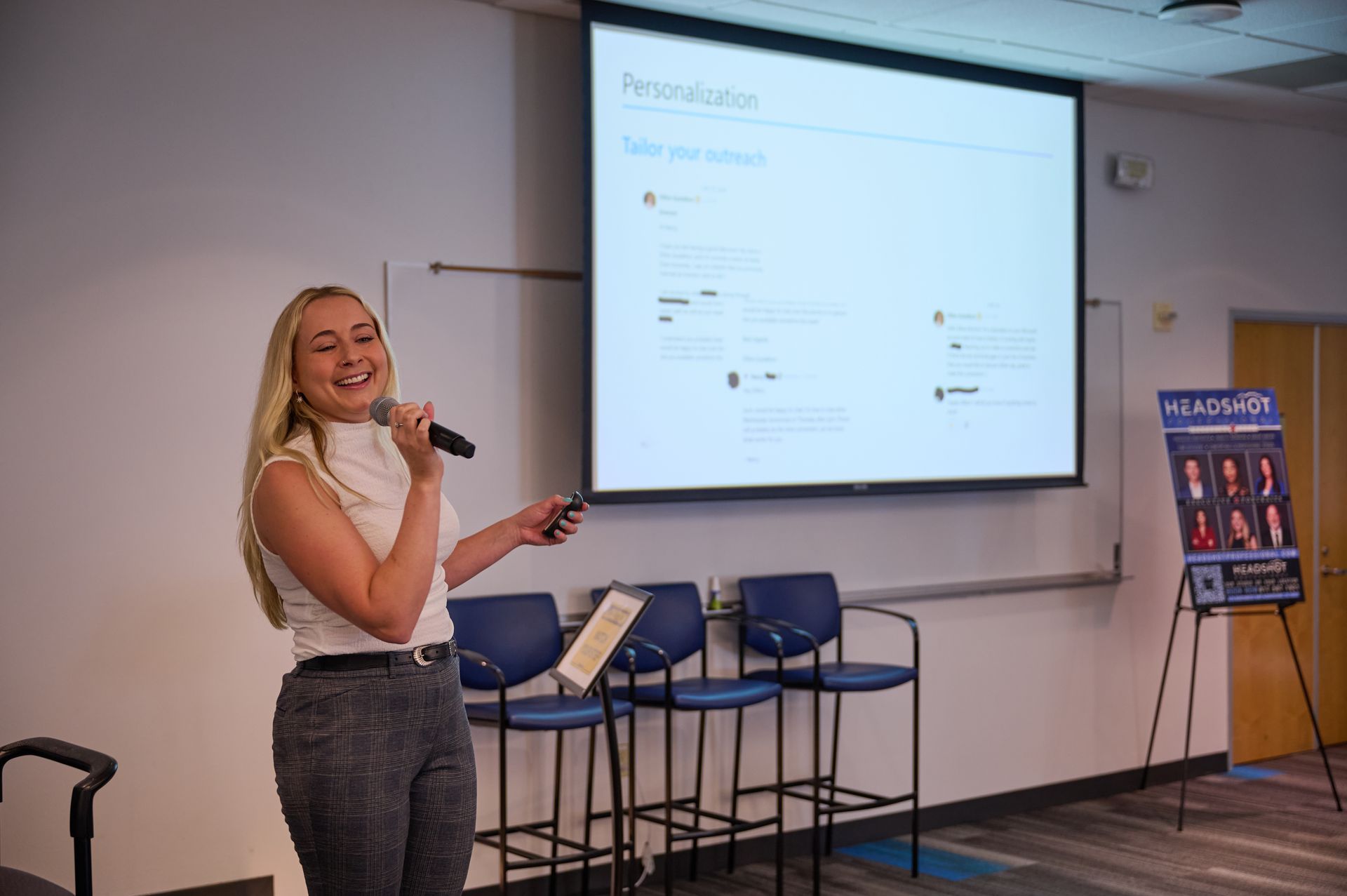 A woman is giving a presentation in front of a large screen in a classroom.