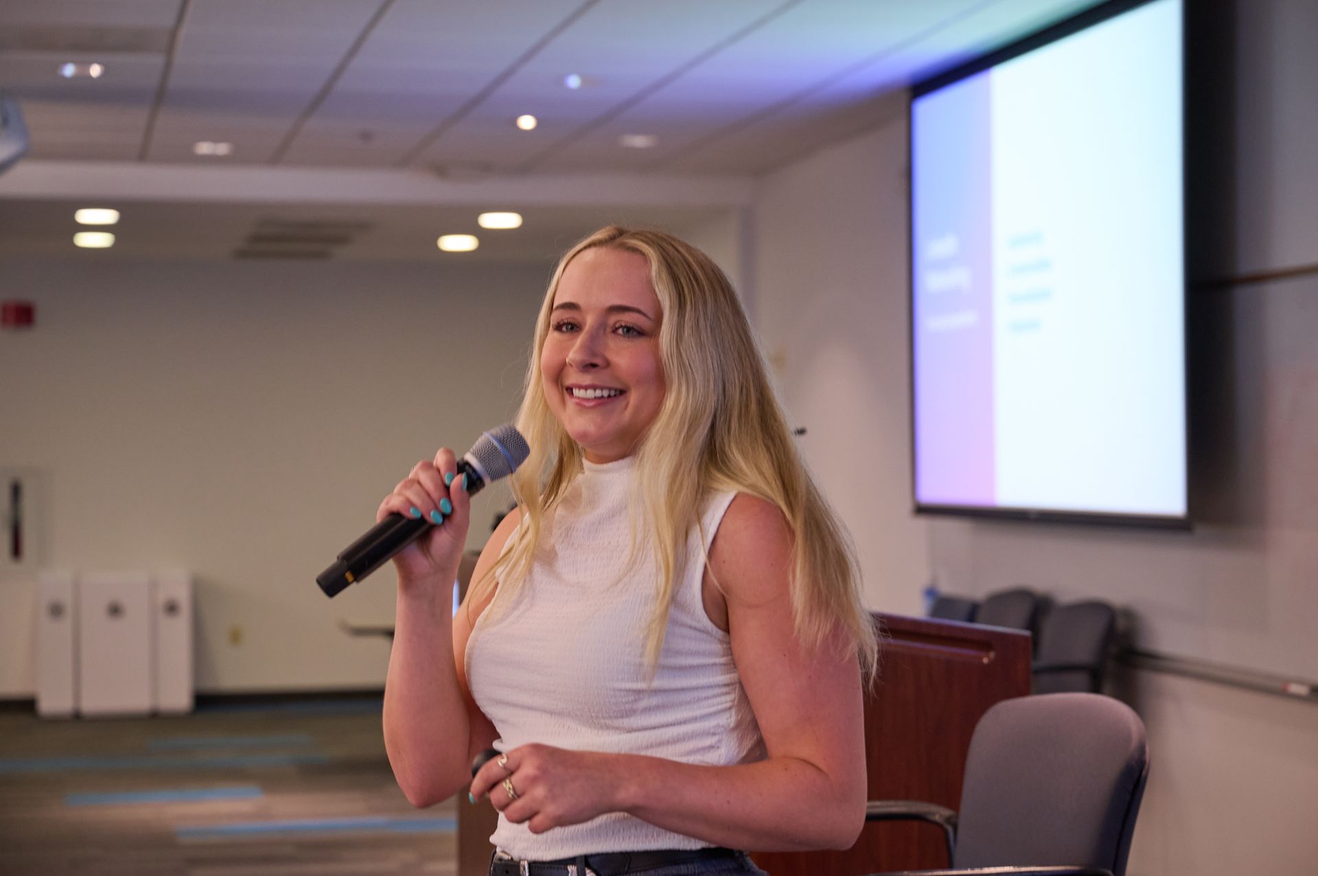 A woman is holding a microphone in front of a projection screen.