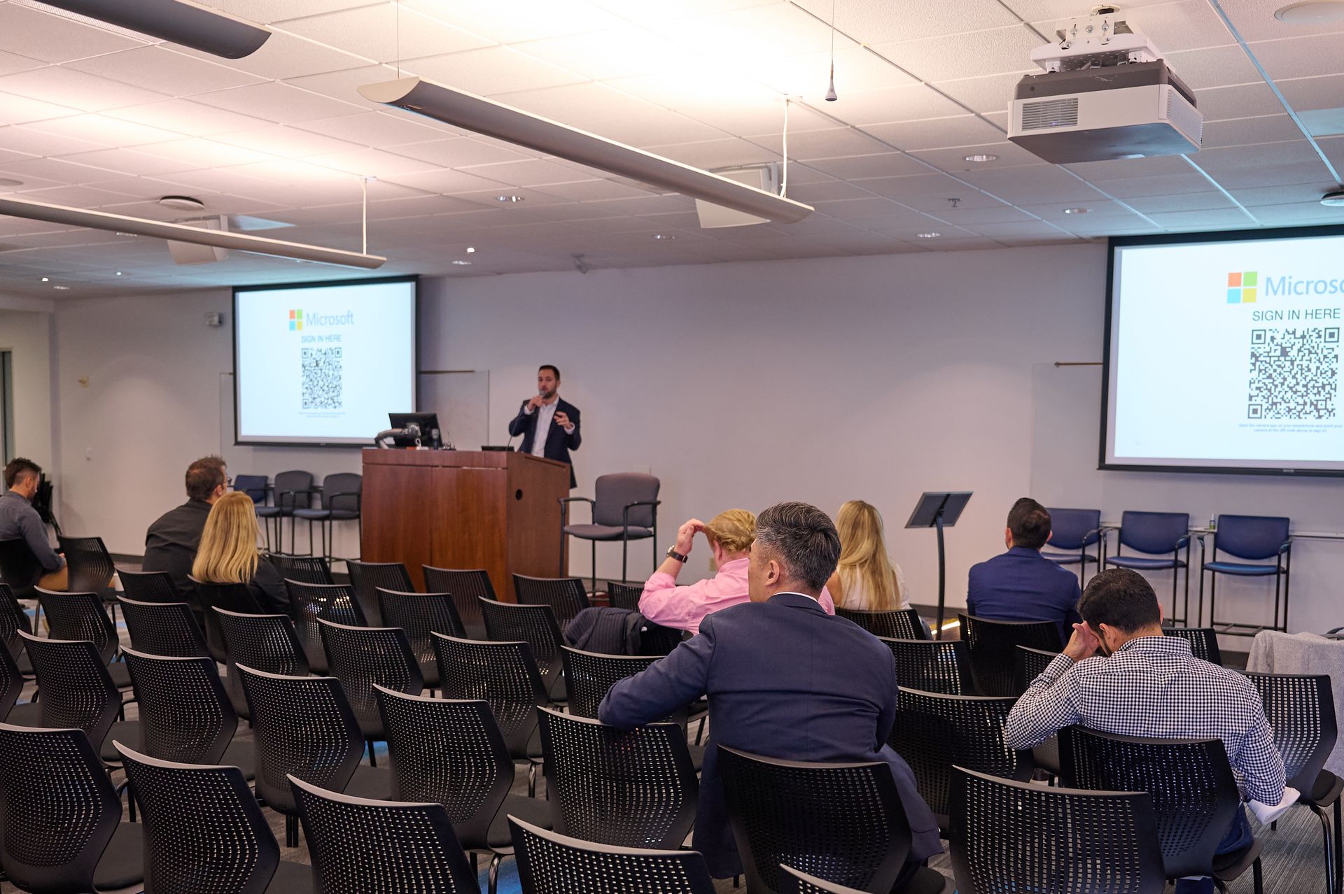 A man is giving a presentation to a group of people in a lecture hall.
