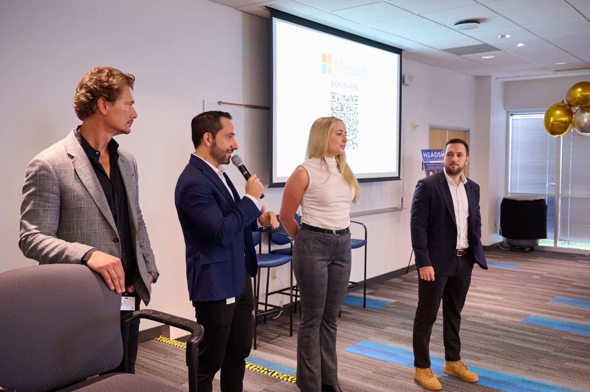 A group of people are standing in front of a projector screen in a room.