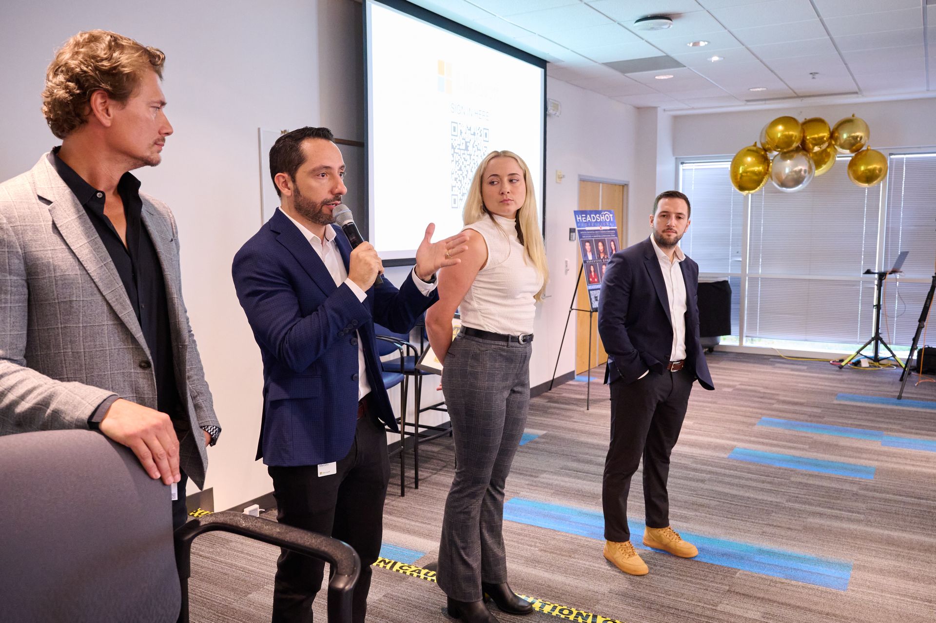 A group of people are standing in front of a large screen in a room.