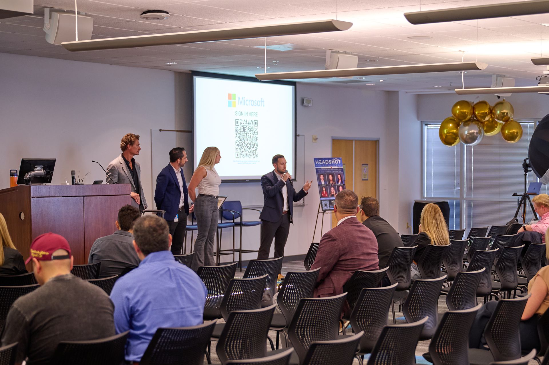 A group of people are sitting in a lecture hall watching a presentation.