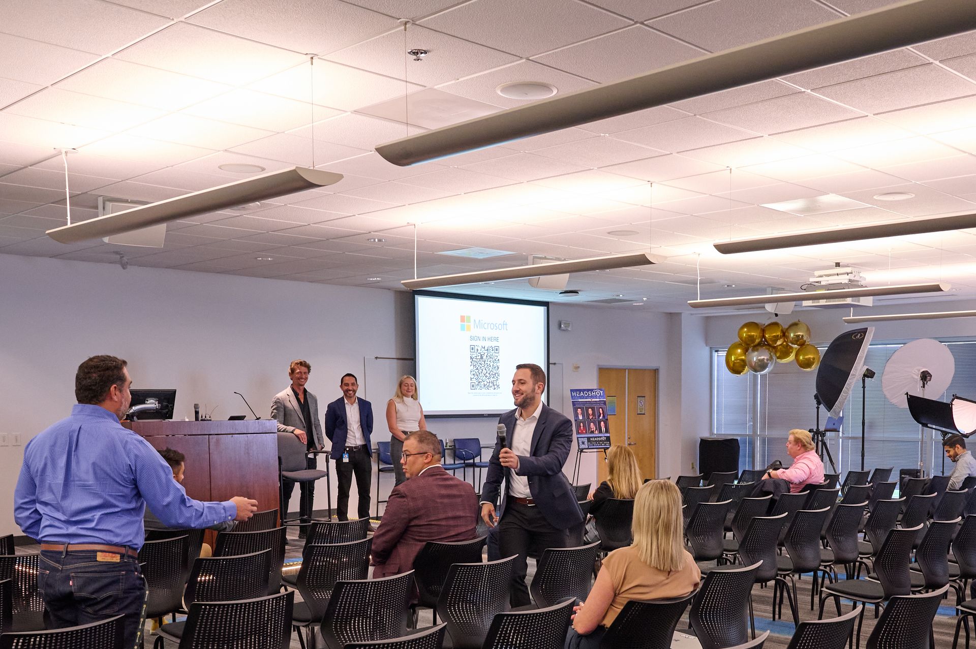 A group of people are sitting in a large room watching a presentation.