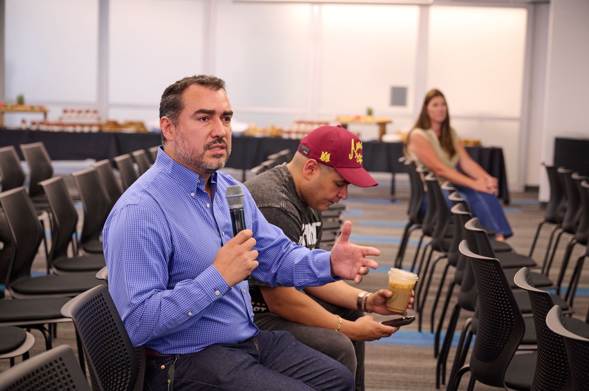A man is holding a microphone while sitting in a row of chairs.