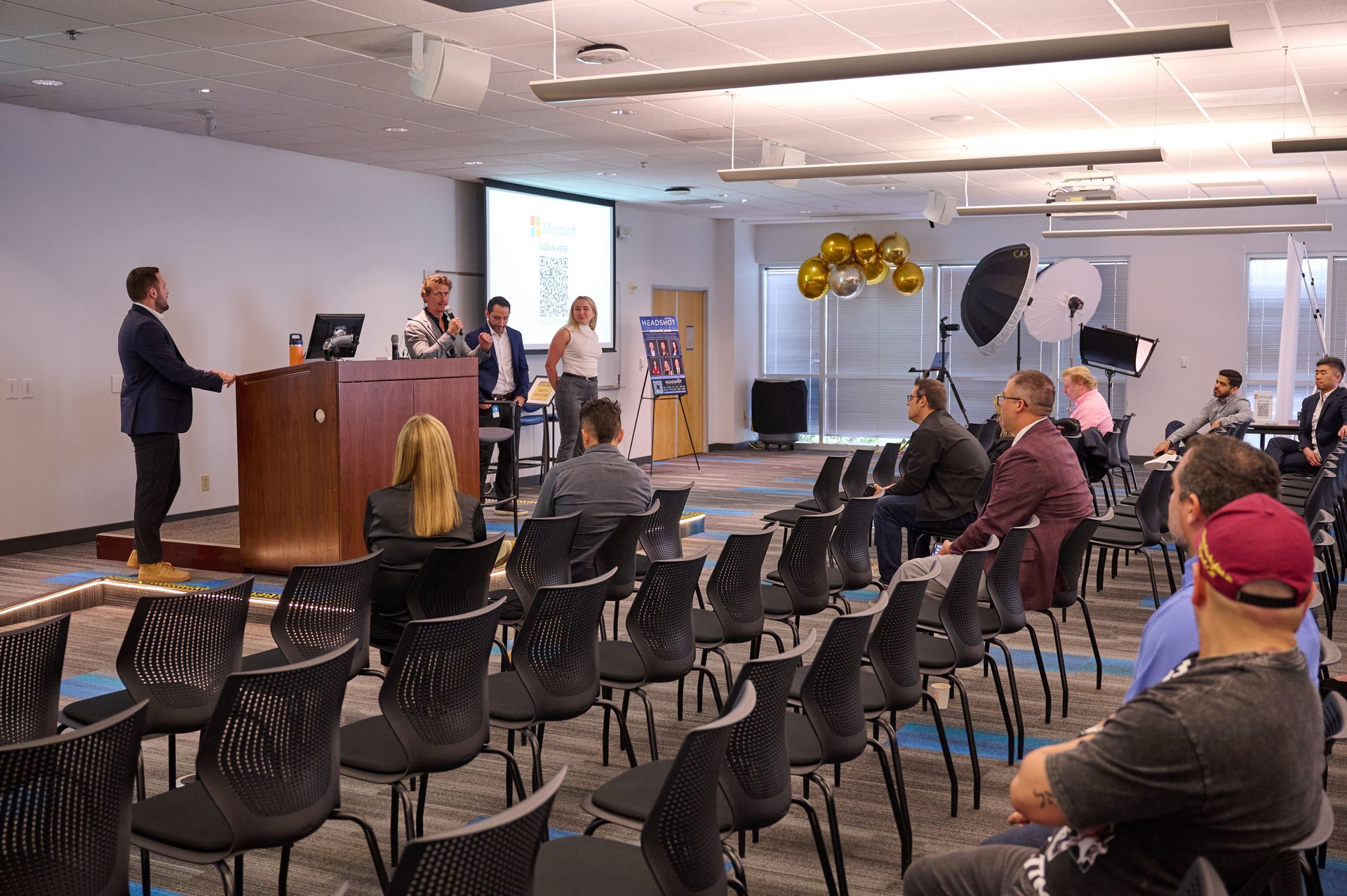 A group of people are sitting in chairs in front of a podium in a conference room.