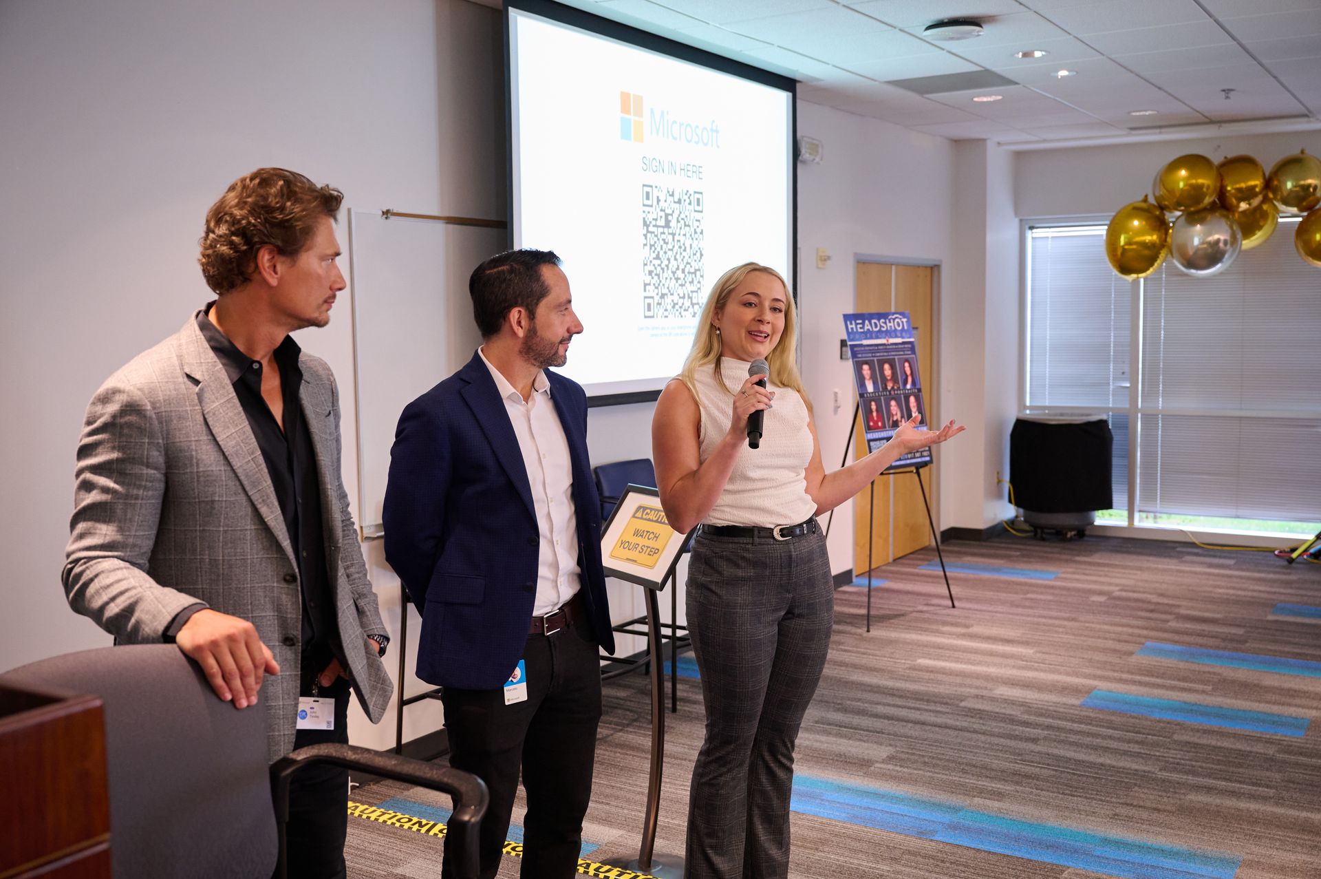 A group of people are standing in front of a large screen in a room.