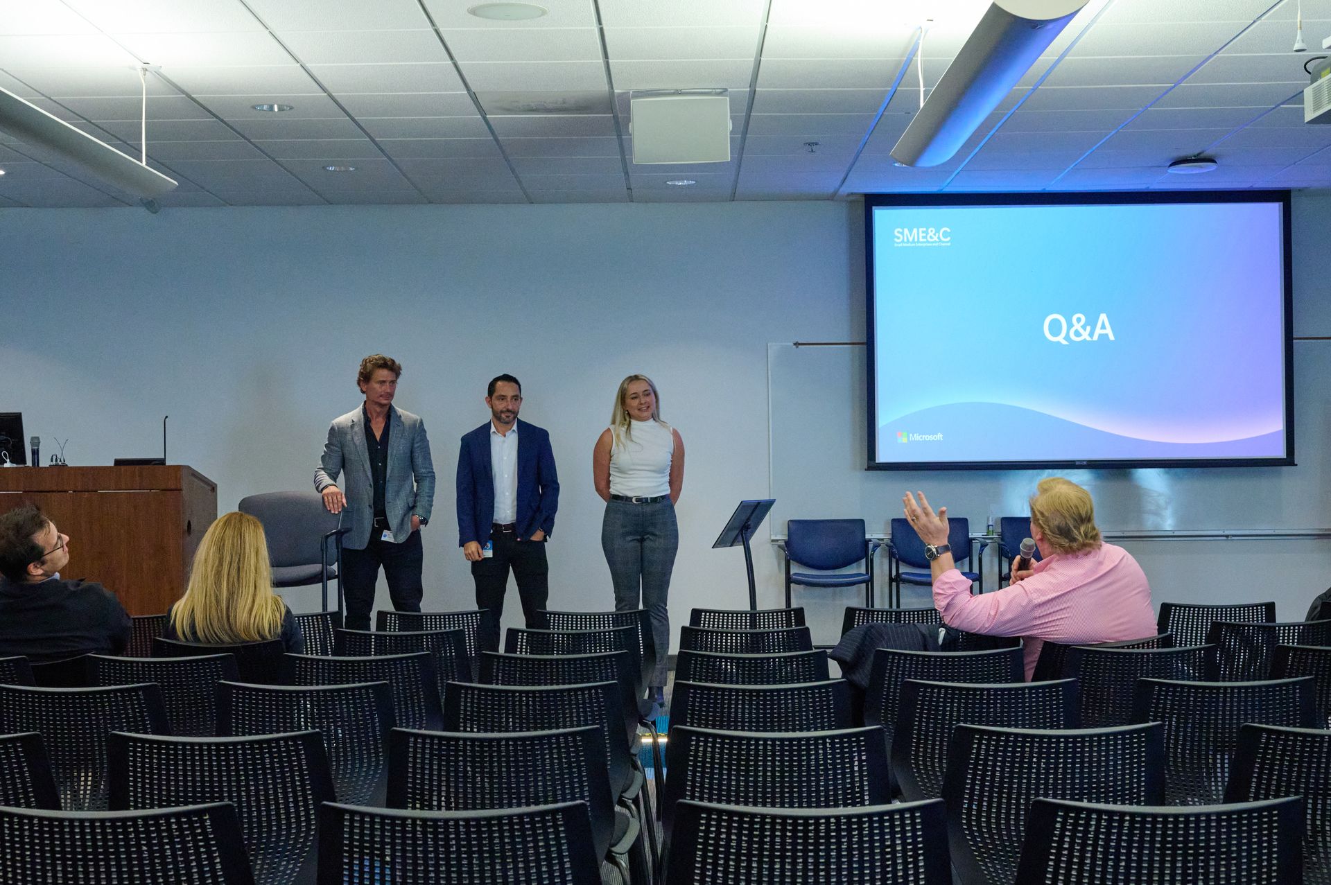 A group of people are standing in front of a large screen that says q & a.