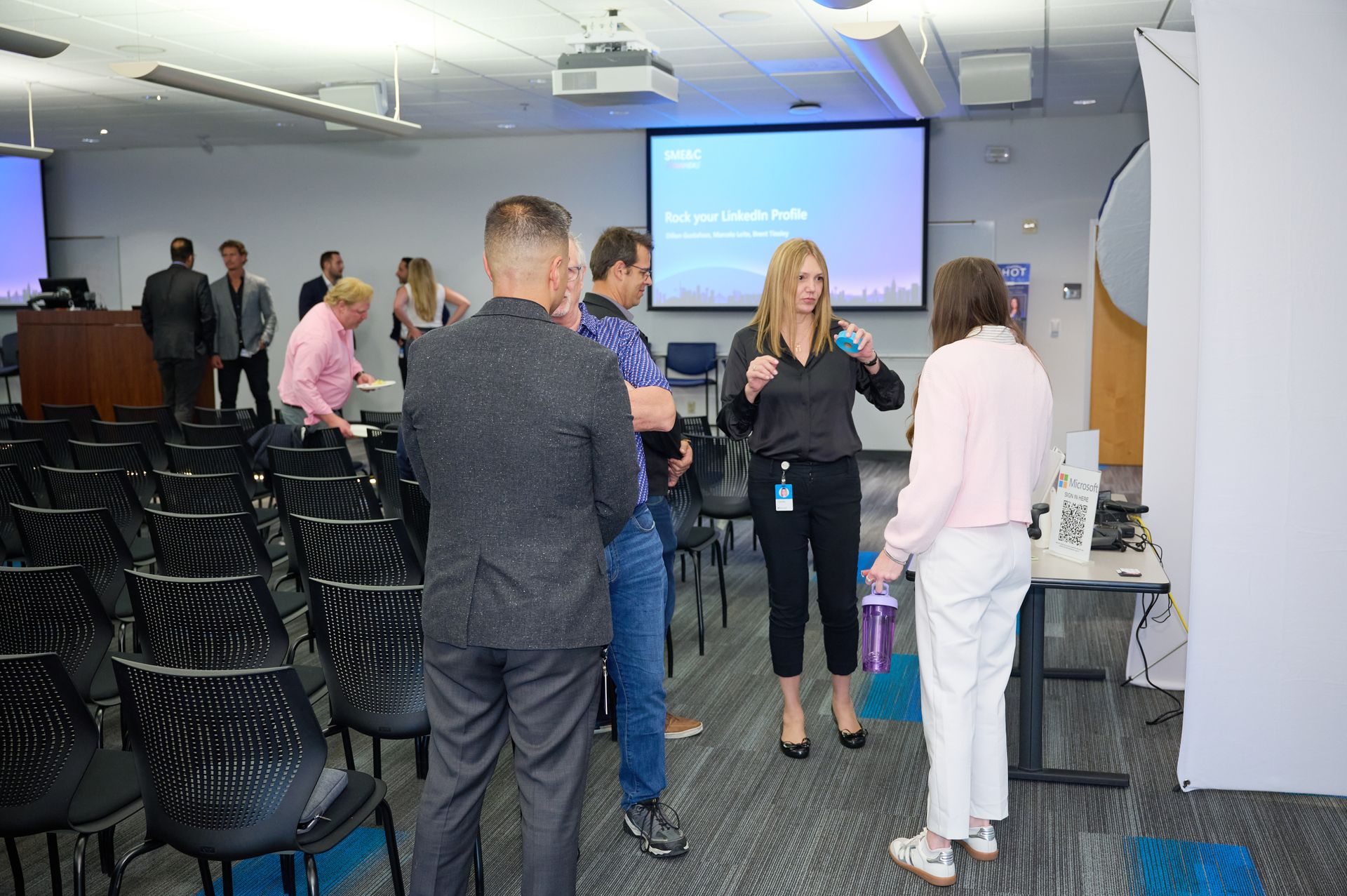 A group of people are standing in a room with a projector screen.