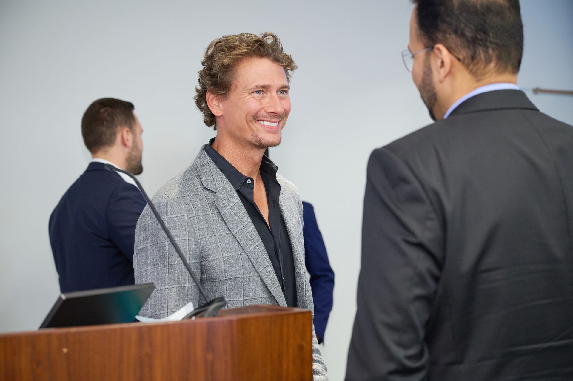 A man in a suit is standing at a podium talking to another man.