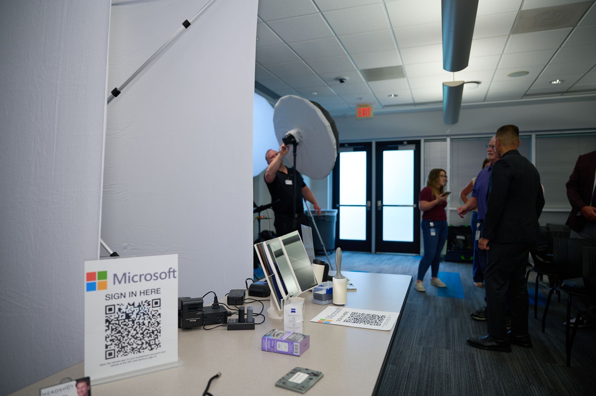 A group of people are standing around a table with a sign that says microsoft on it.
