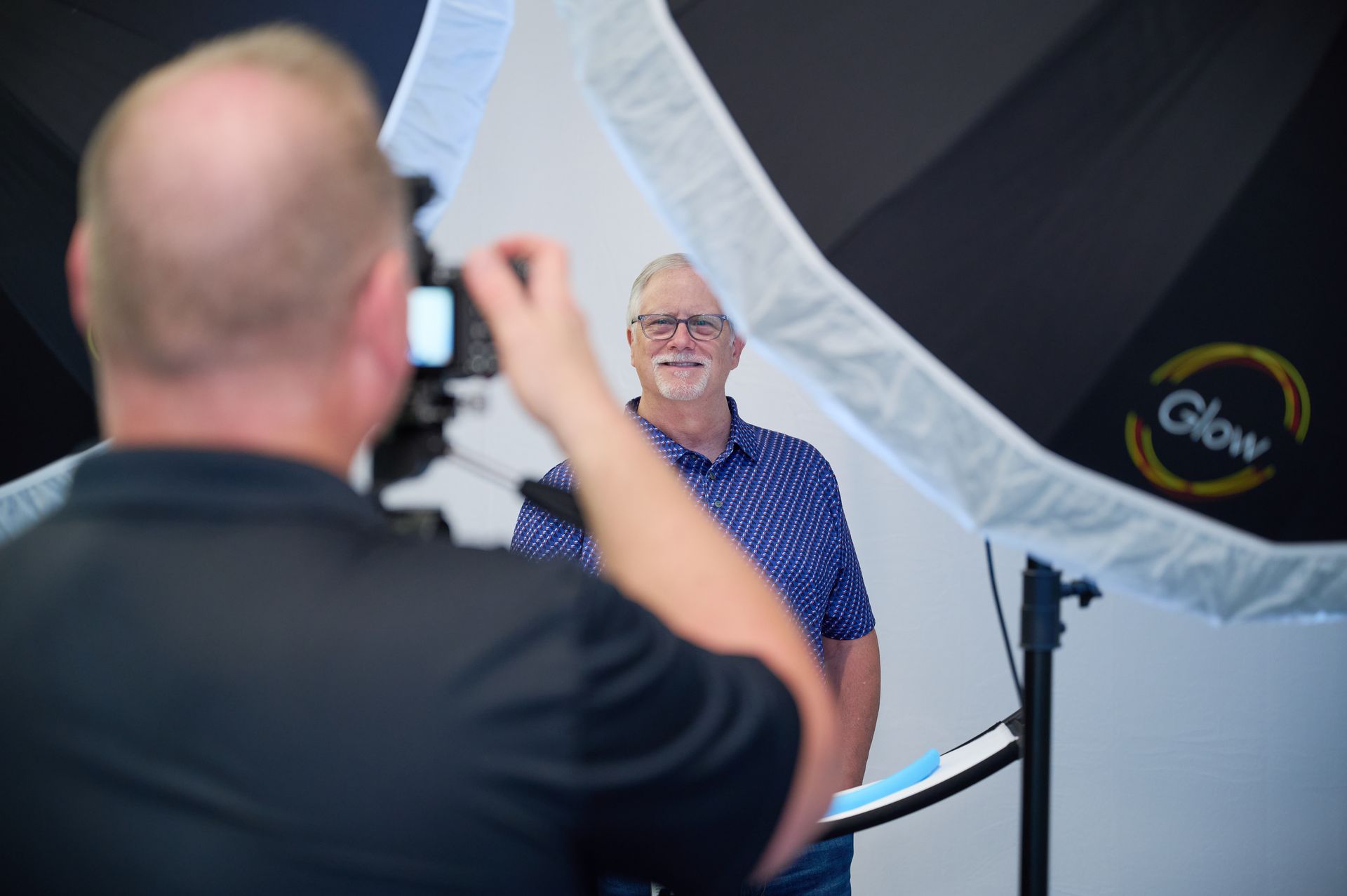 A man is taking a picture of another man in front of a glow light.