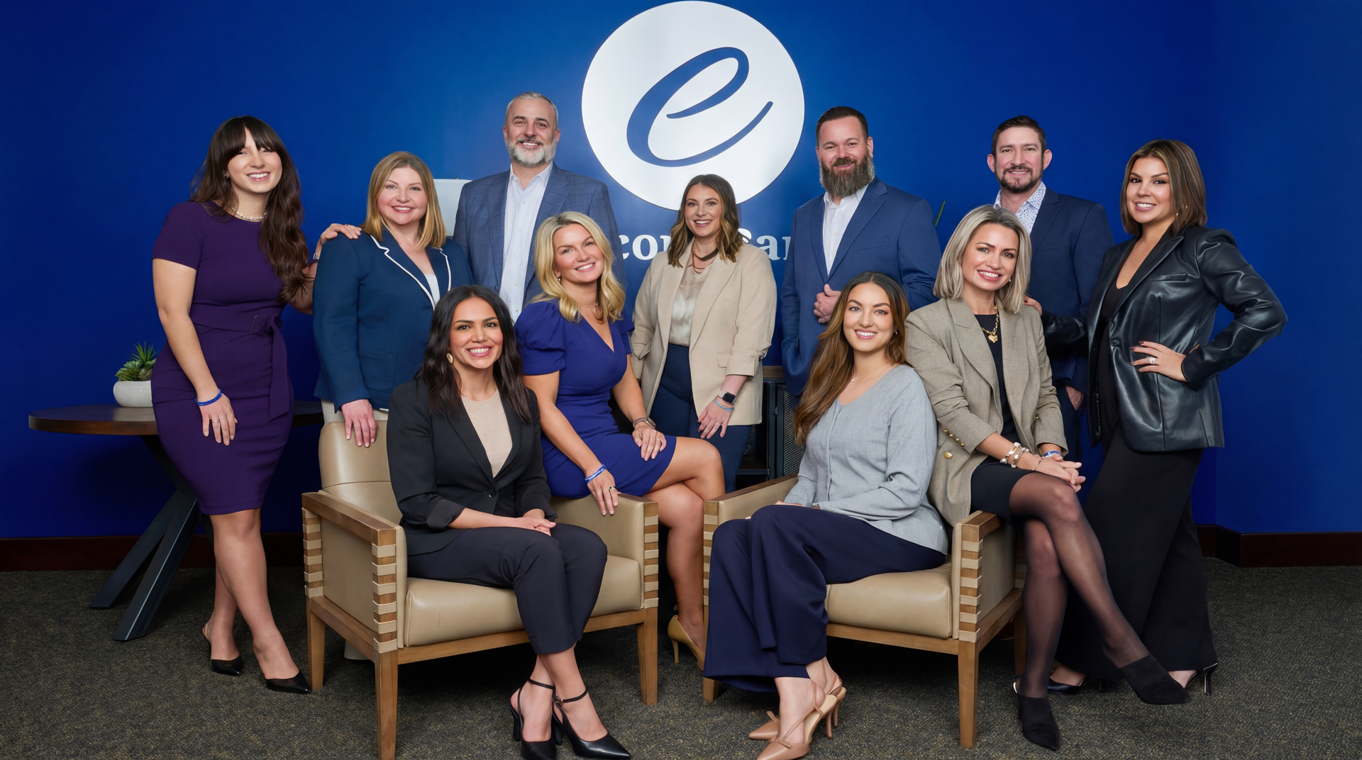 Ten people posing in a studio portrait against a white background, wearing business and casual attire.