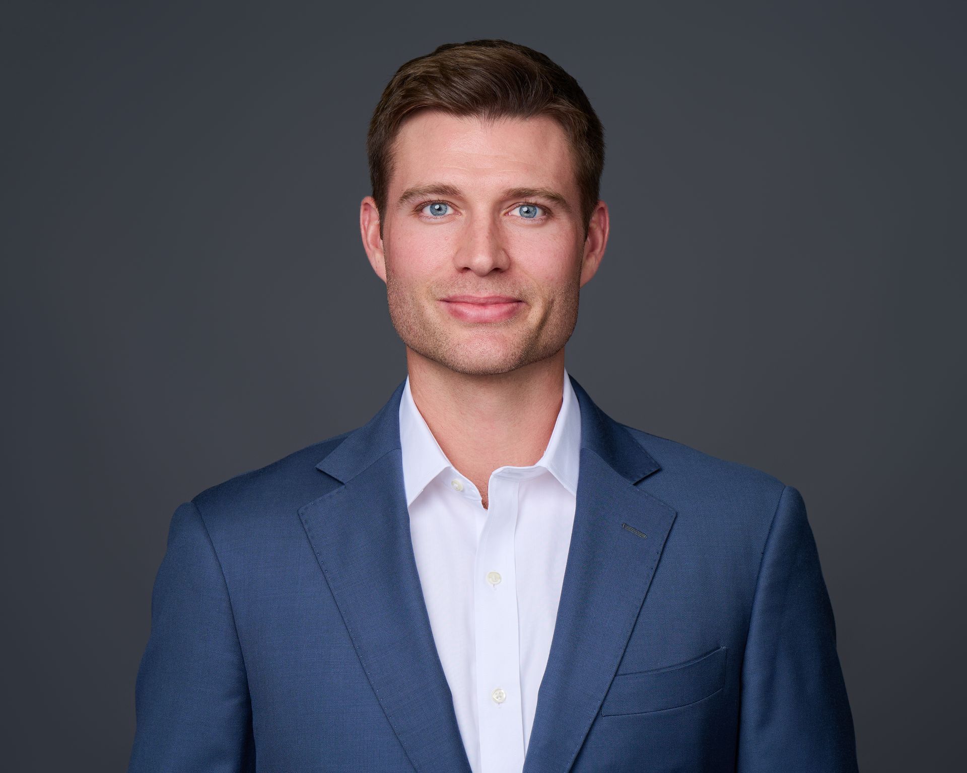 A man in a blue suit and white shirt is smiling for the camera.