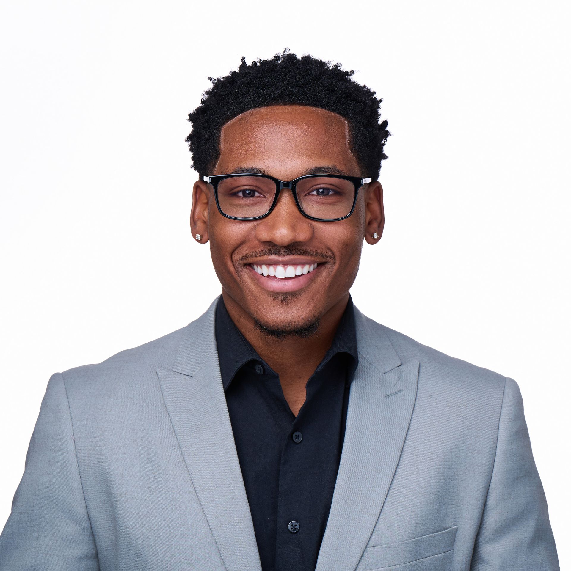 A man wearing glasses and a suit is smiling for the camera.
