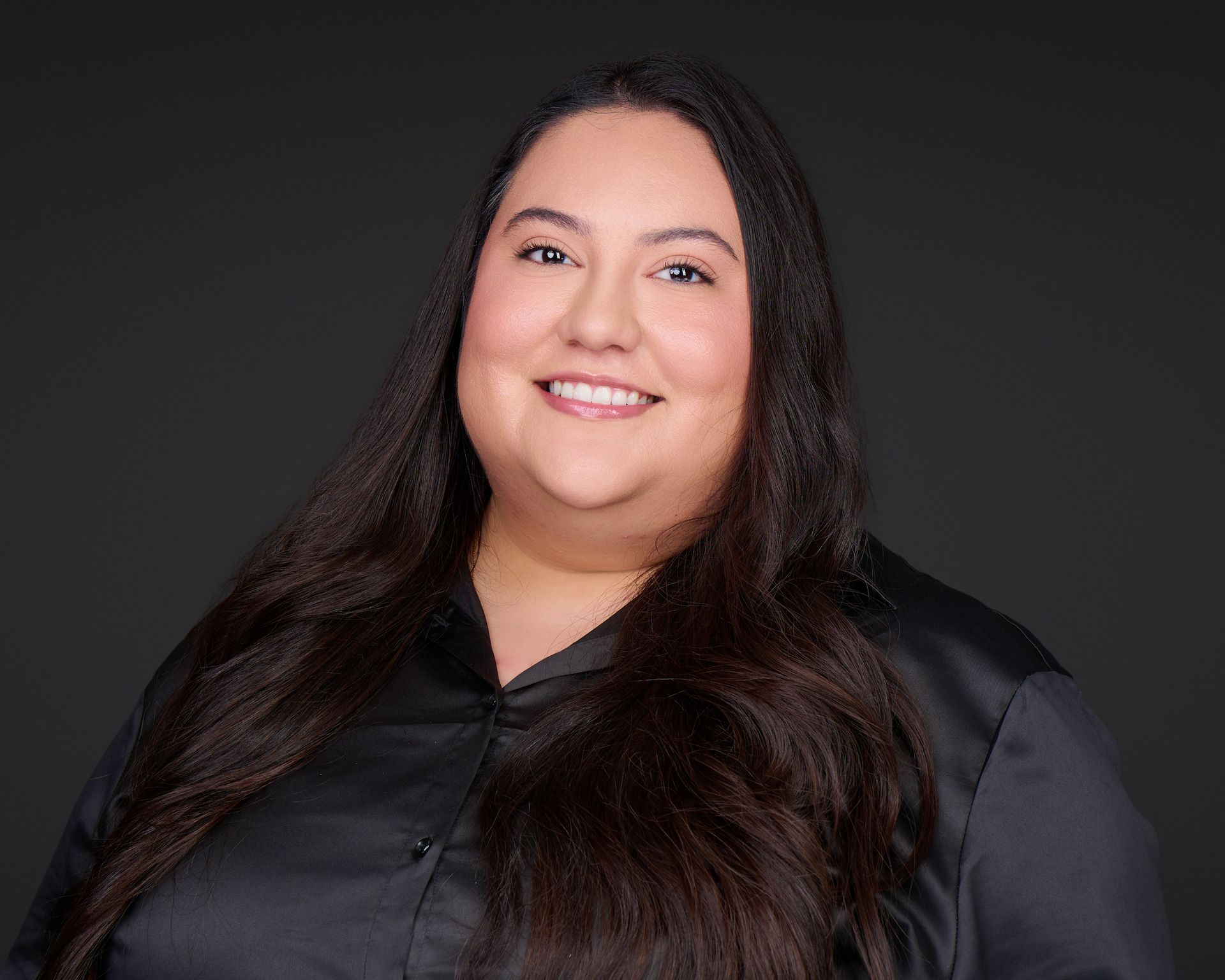 Smiling person in a black shirt against a dark gray background.