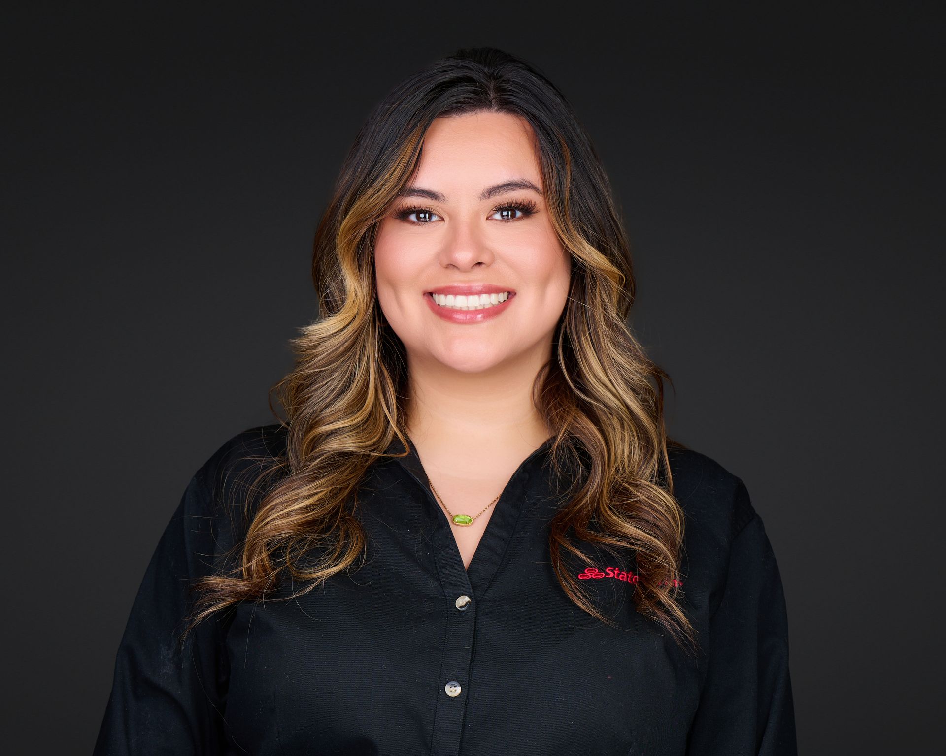 Smiling woman in a black shirt against a dark studio background