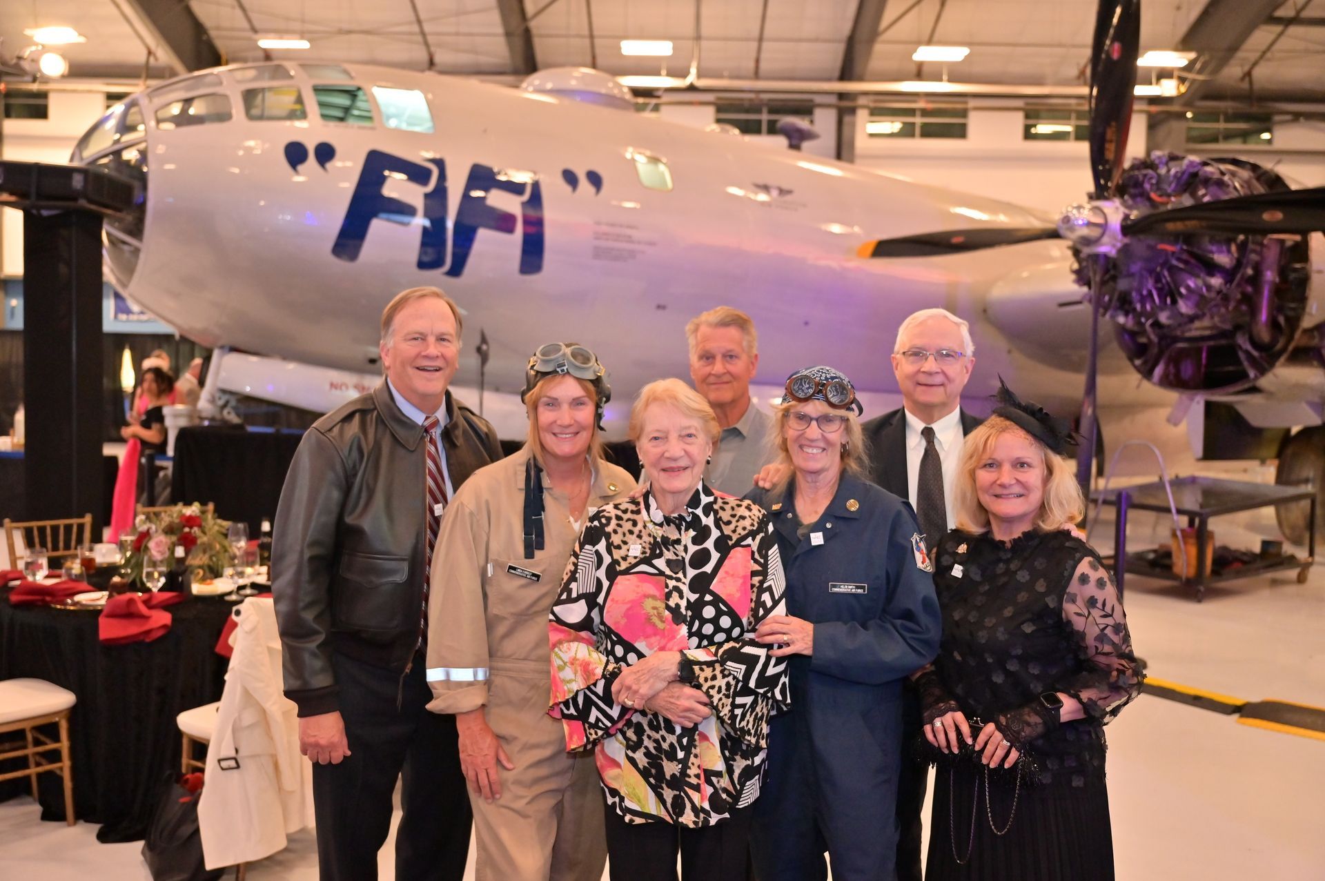 A group of people are posing for a picture in front of a plane that says