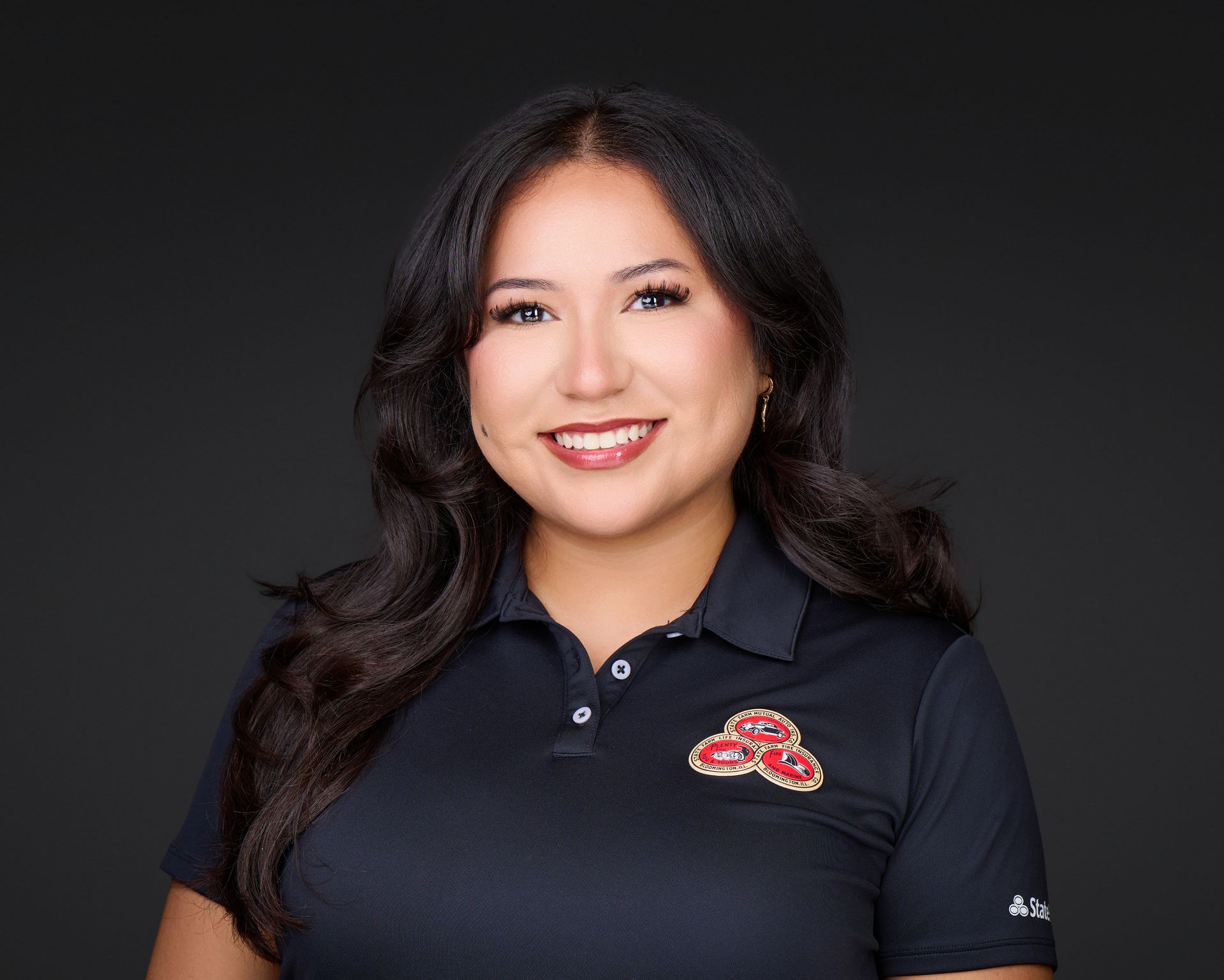 Smiling person in a black polo shirt with a red logo on a dark background