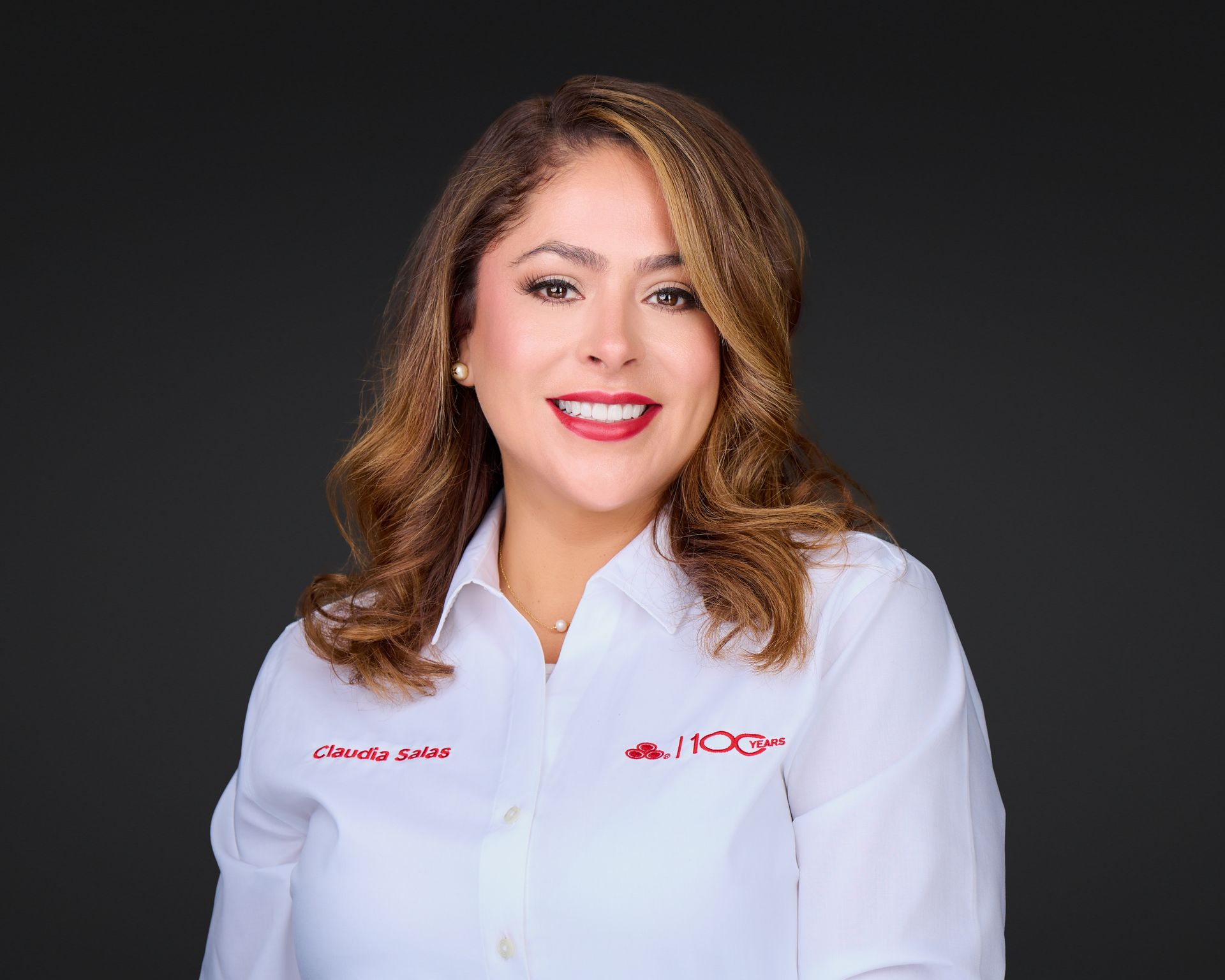 Portrait of a smiling professional in a white lab coat against a dark background