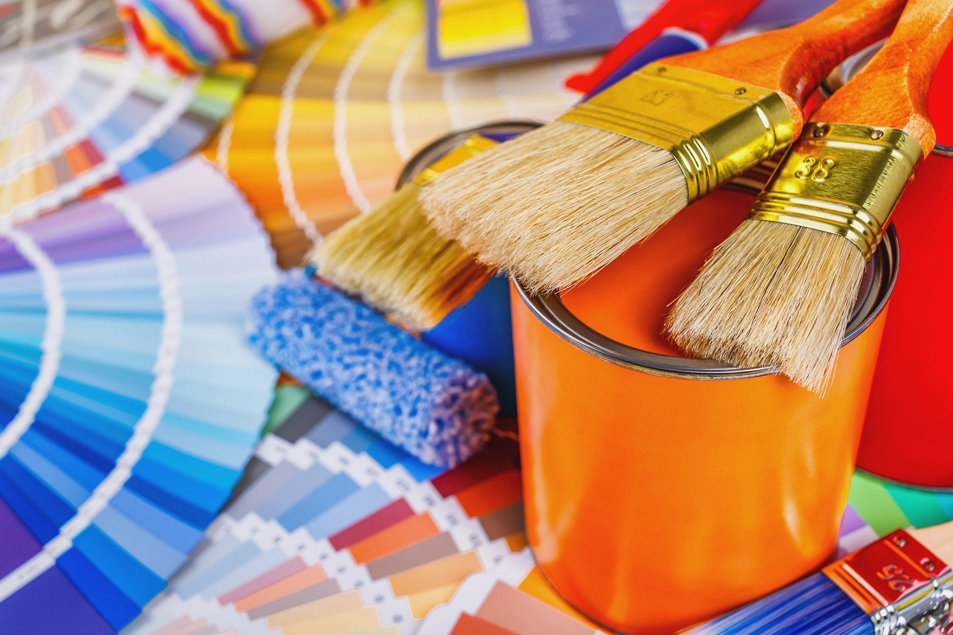 Paintbrushes in an orange can beside color swatches and paint samples
