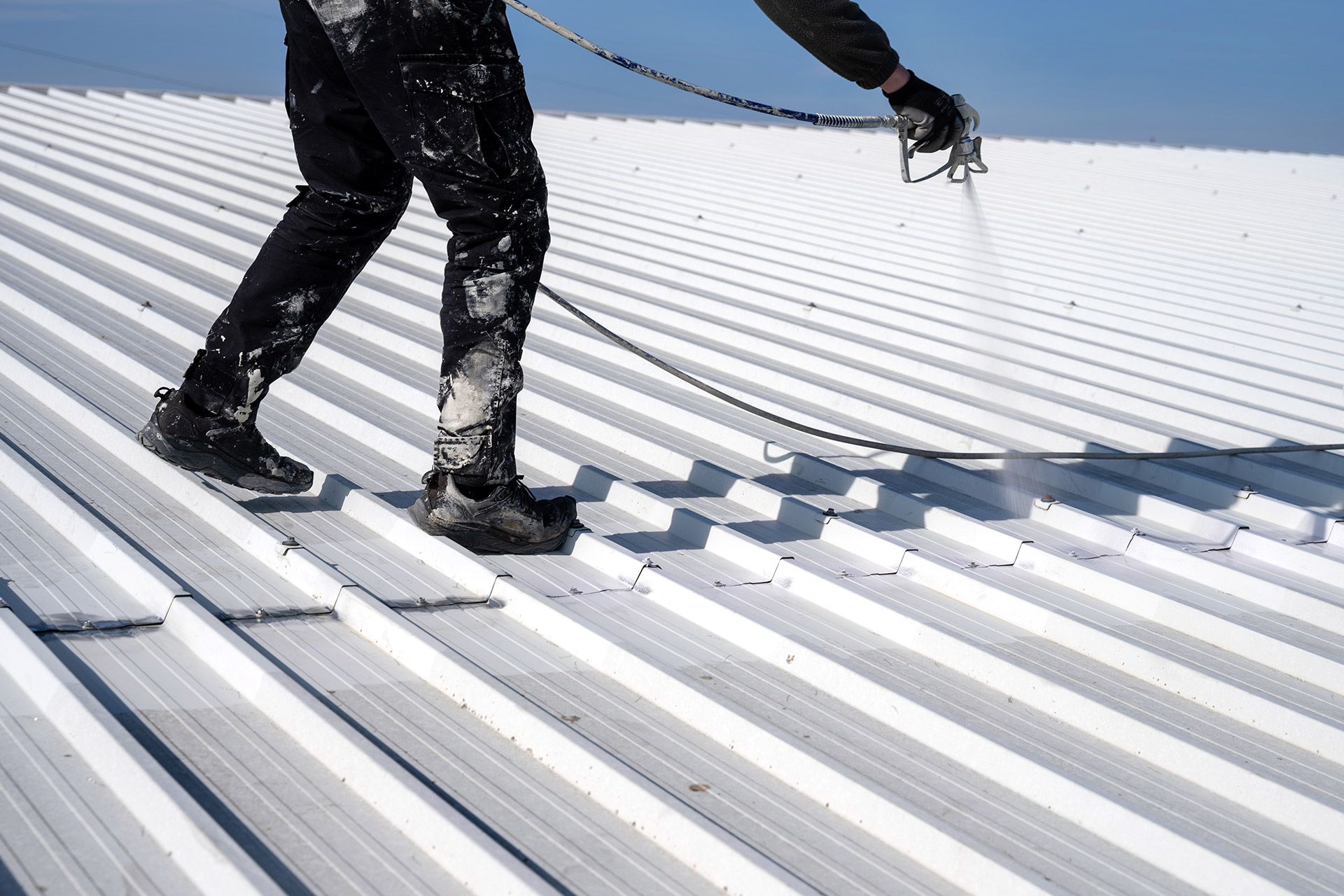 Worker walking on a white corrugated metal roof in snowy conditions