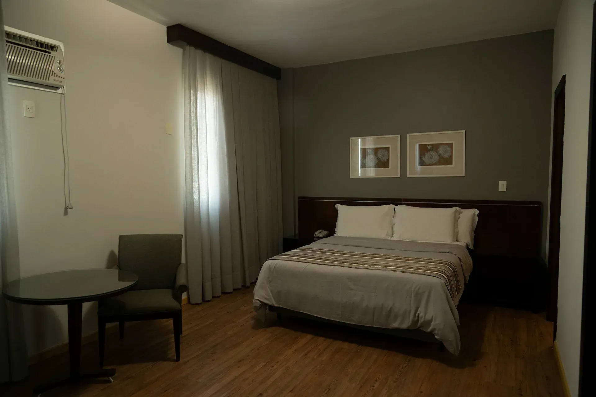 Um quarto de hotel com uma cama, cadeira, mesa e janela.