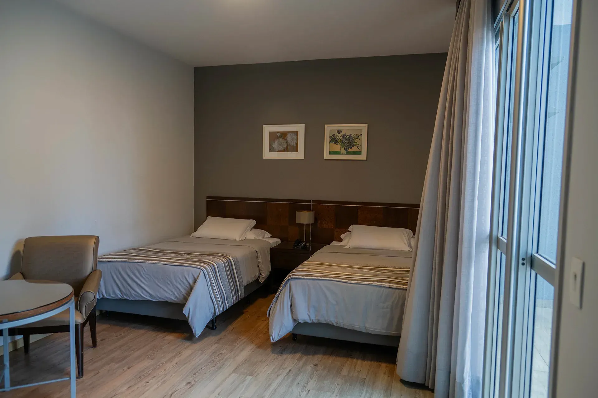 Um quarto de hotel com duas camas, uma cadeira e uma mesa.