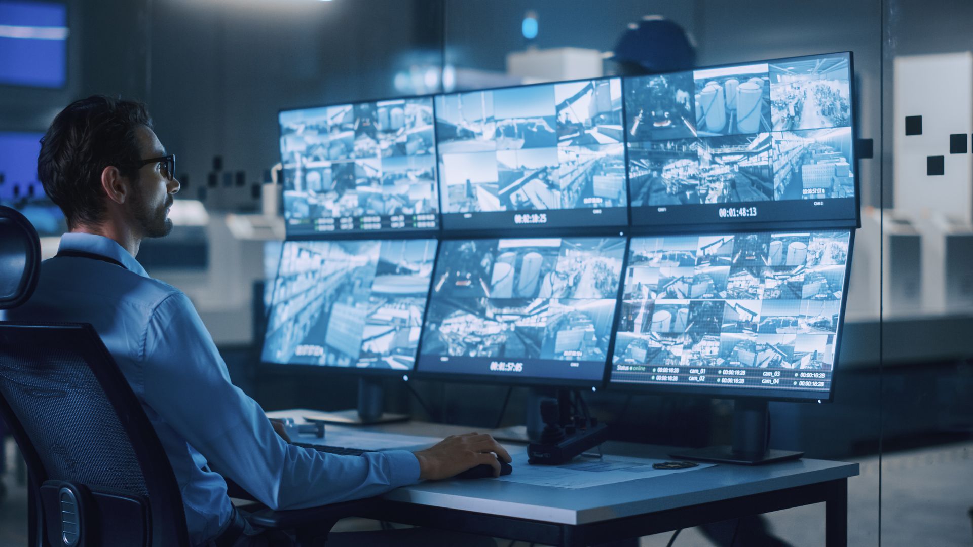 Security operator monitoring multiple video surveillance feeds on a control room workstation.