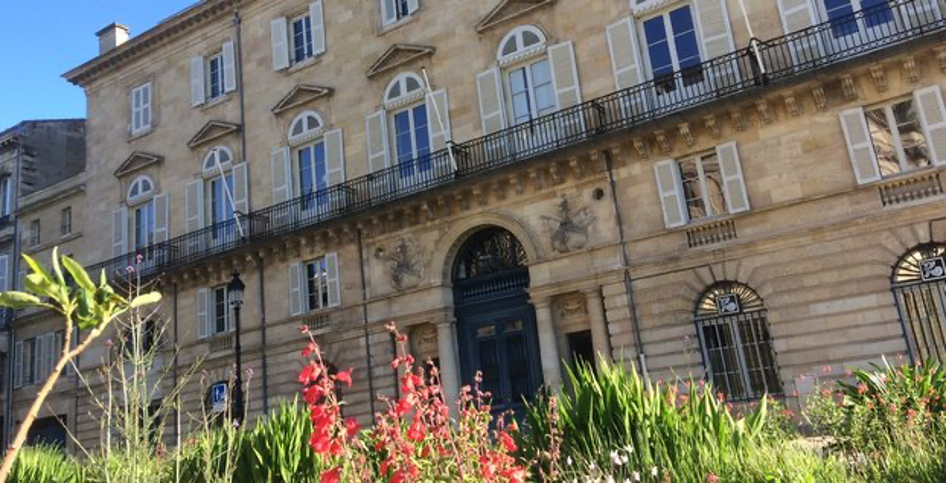 Un grand bâtiment avec beaucoup de fenêtres et de fleurs devant.