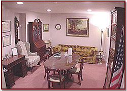 Cozy office with desk, chairs, lamp, paintings, and an American flag in the corner
